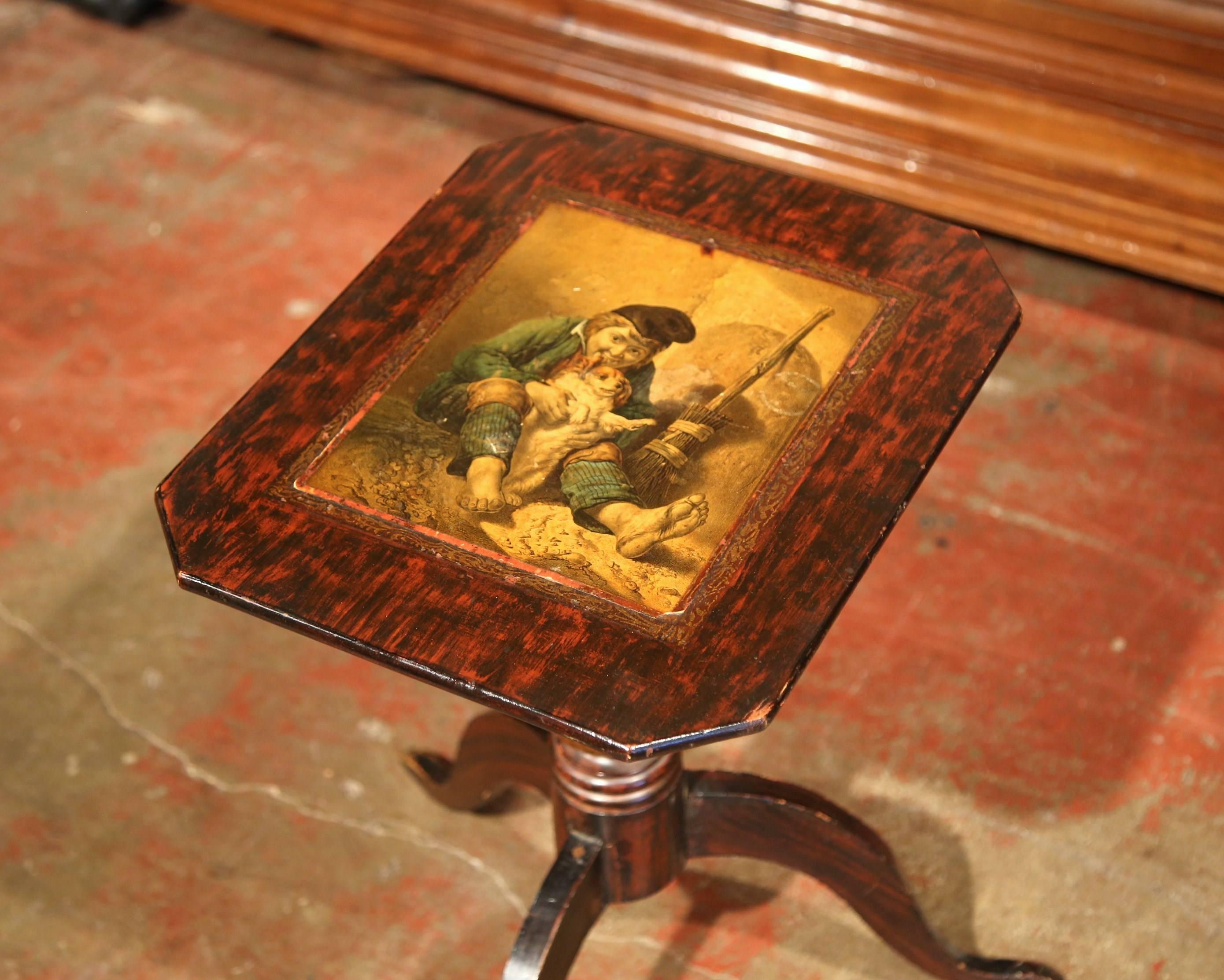 This elegant, rectangular side table was crafted in England, circa 1870. The mahogany pedestal table has angled corners, and the surface features a painted scene of a young boy in 19th century costume playing with his dog. The carved, turned base