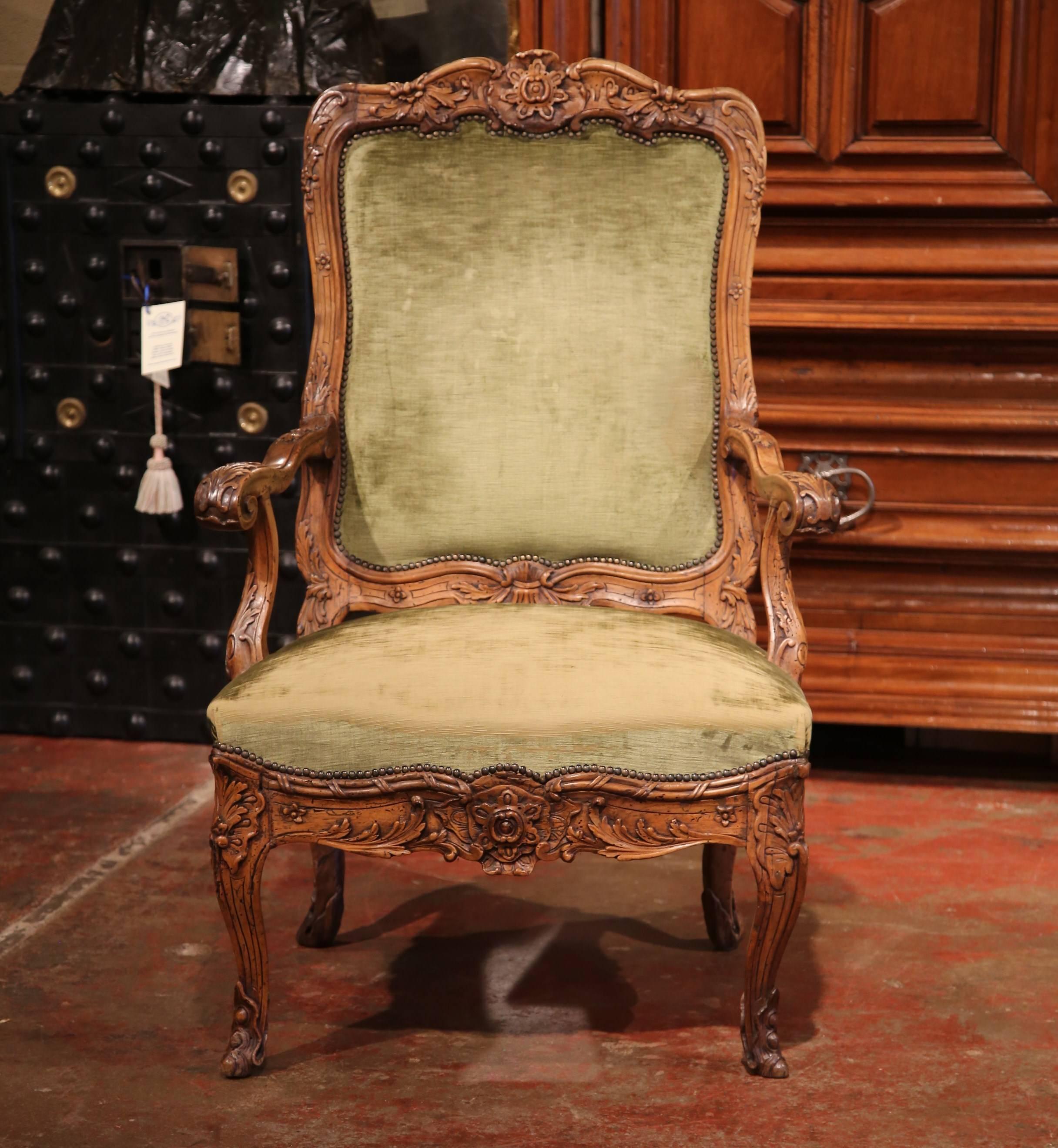 Beautifully carved antique armchair from France; crafted, circa 1860, the fruitwood chair features an ornate frame with deep carvings including carved flowers at the top and around the apron, and foliage throughout. The desk armchair is upholstered