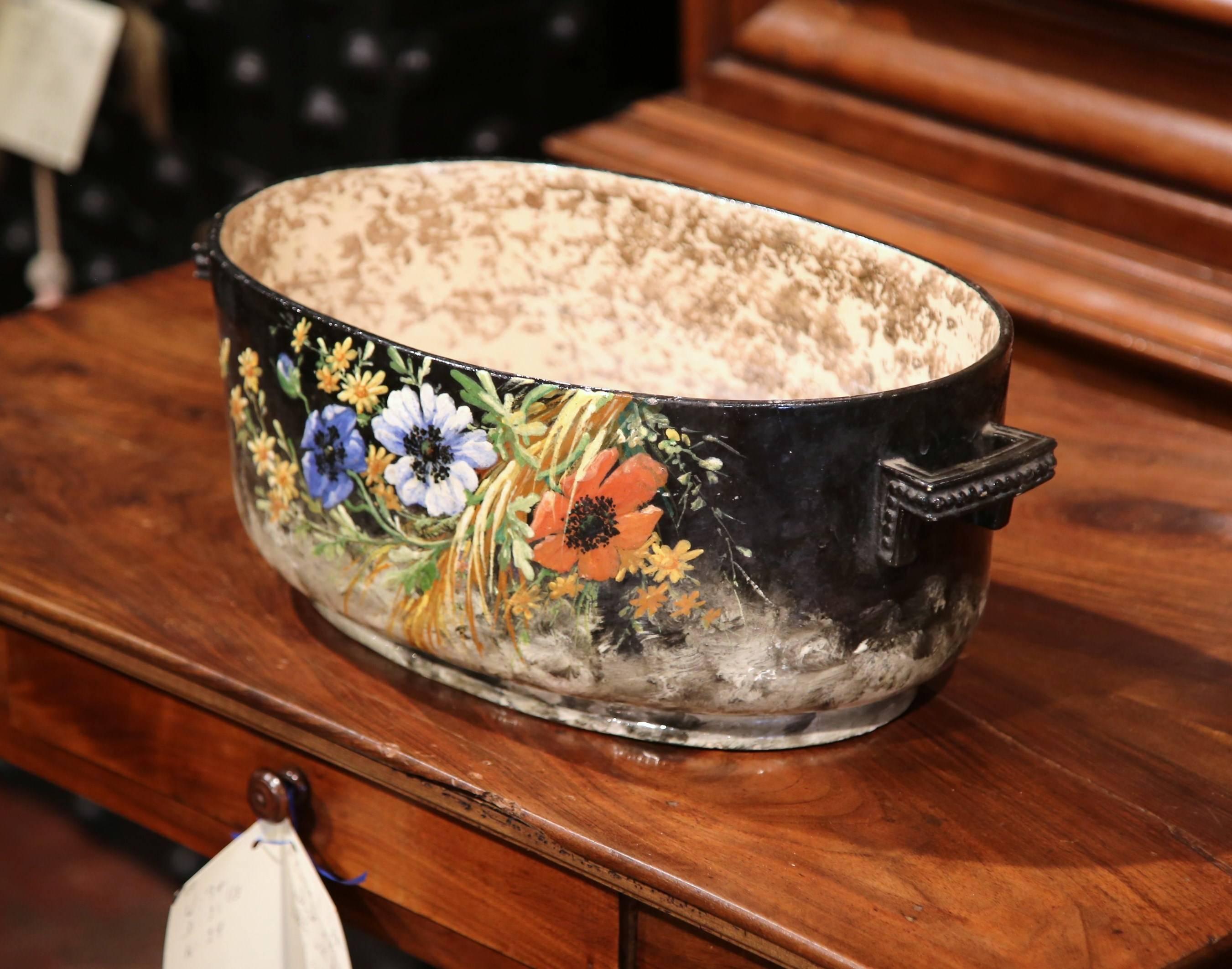 This elegant and colorful planter was hand-painted in Central France, more specifically Montigny-sur-Loing, circa 1920. The antique jardinière has small handles on both ends and features colorful hand painted flowers on both sides. The jardinière is