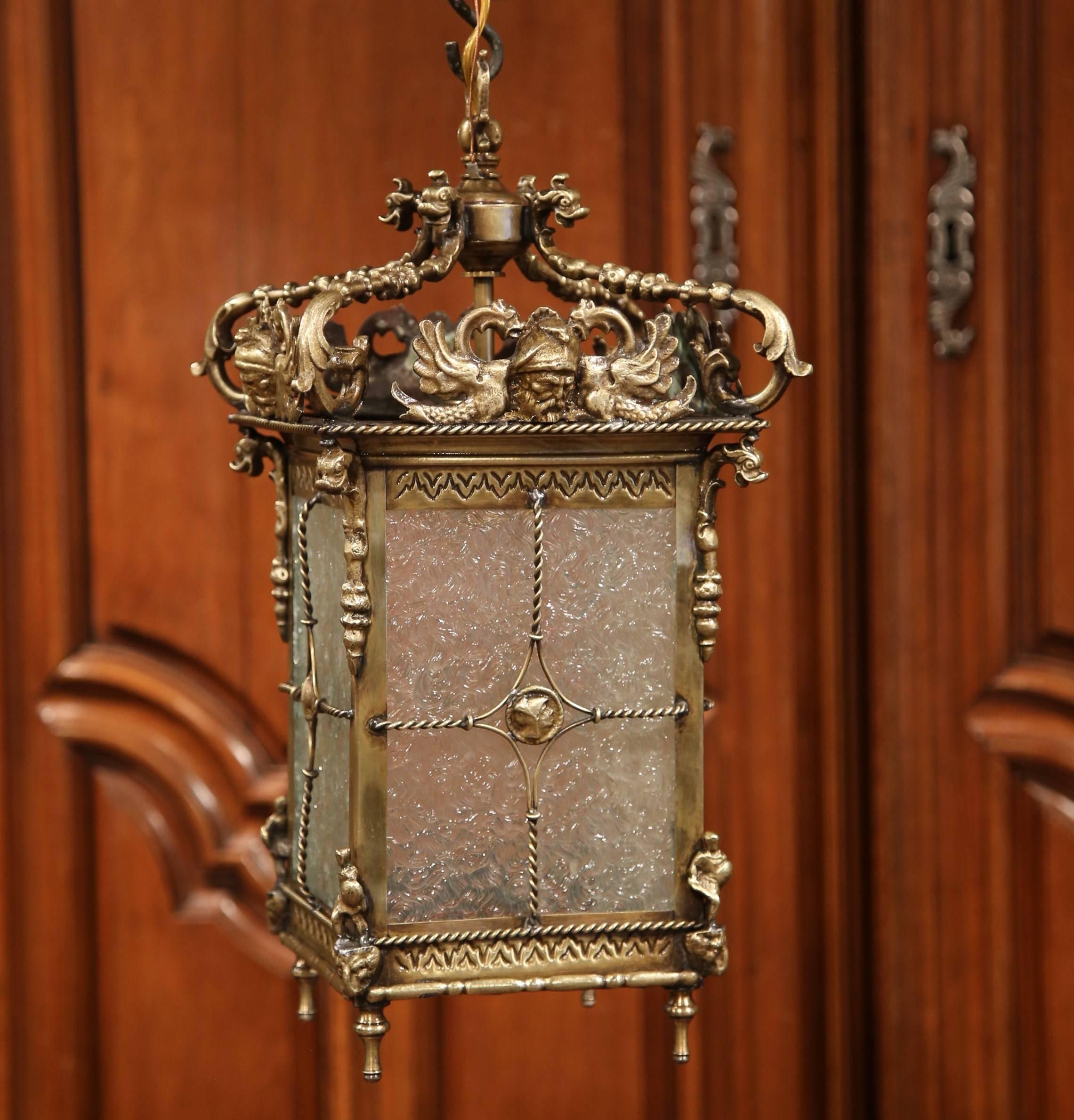 This elegant antique Napoleon III wall lantern was crafted in France, circa 1880. The unique, square light fixture has bottom finials and features classical Roman heads on the top, Roman guards and dolphin heads mounts in each corner, and Roman