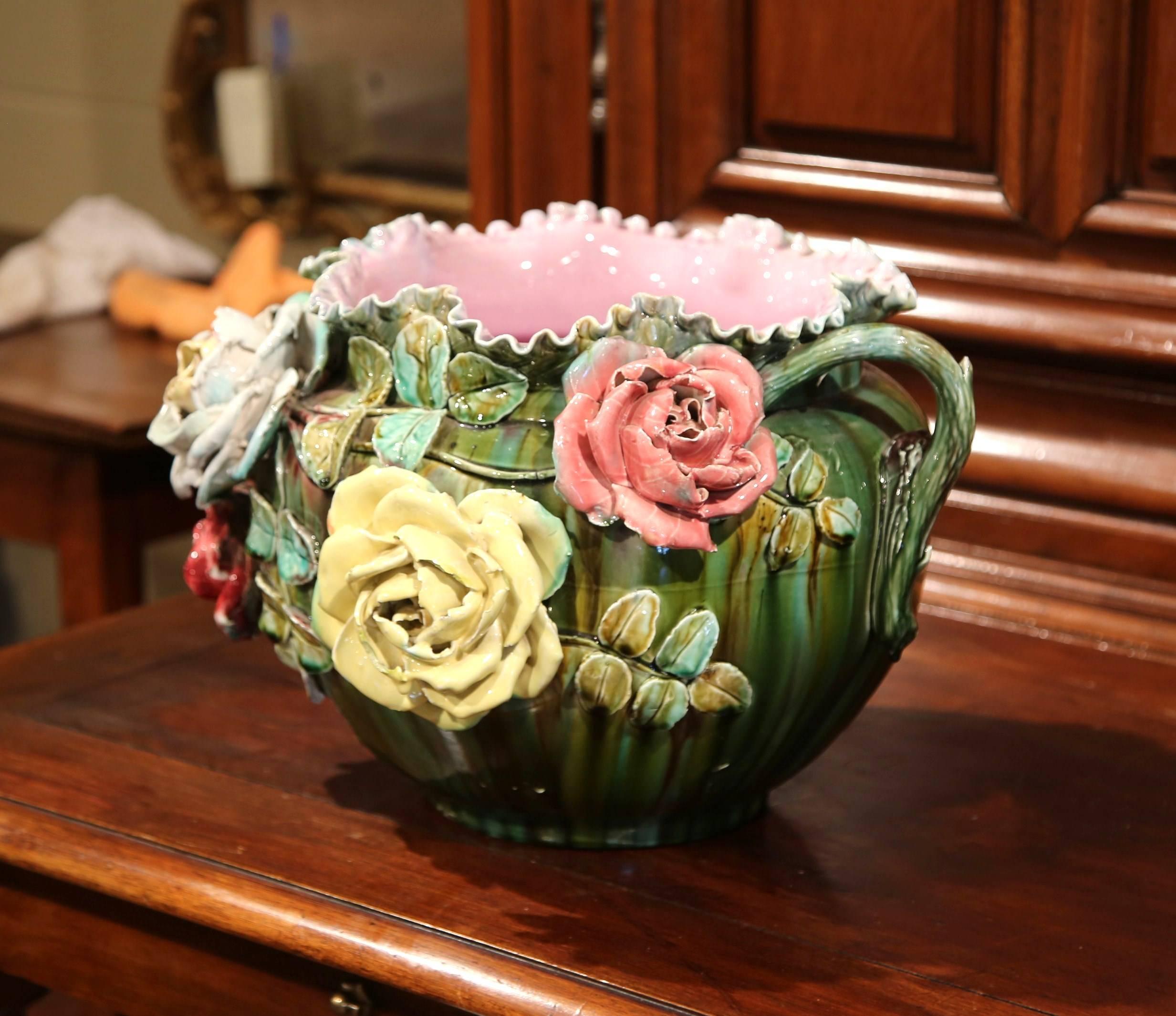 This large, antique Majolica planter was crafted in France, circa 1890. The decorative porcelain cachepot with scalloped edge features four colorful, high relief roses embellished with green leaves. The round, ceramic jardiniere is painted in a