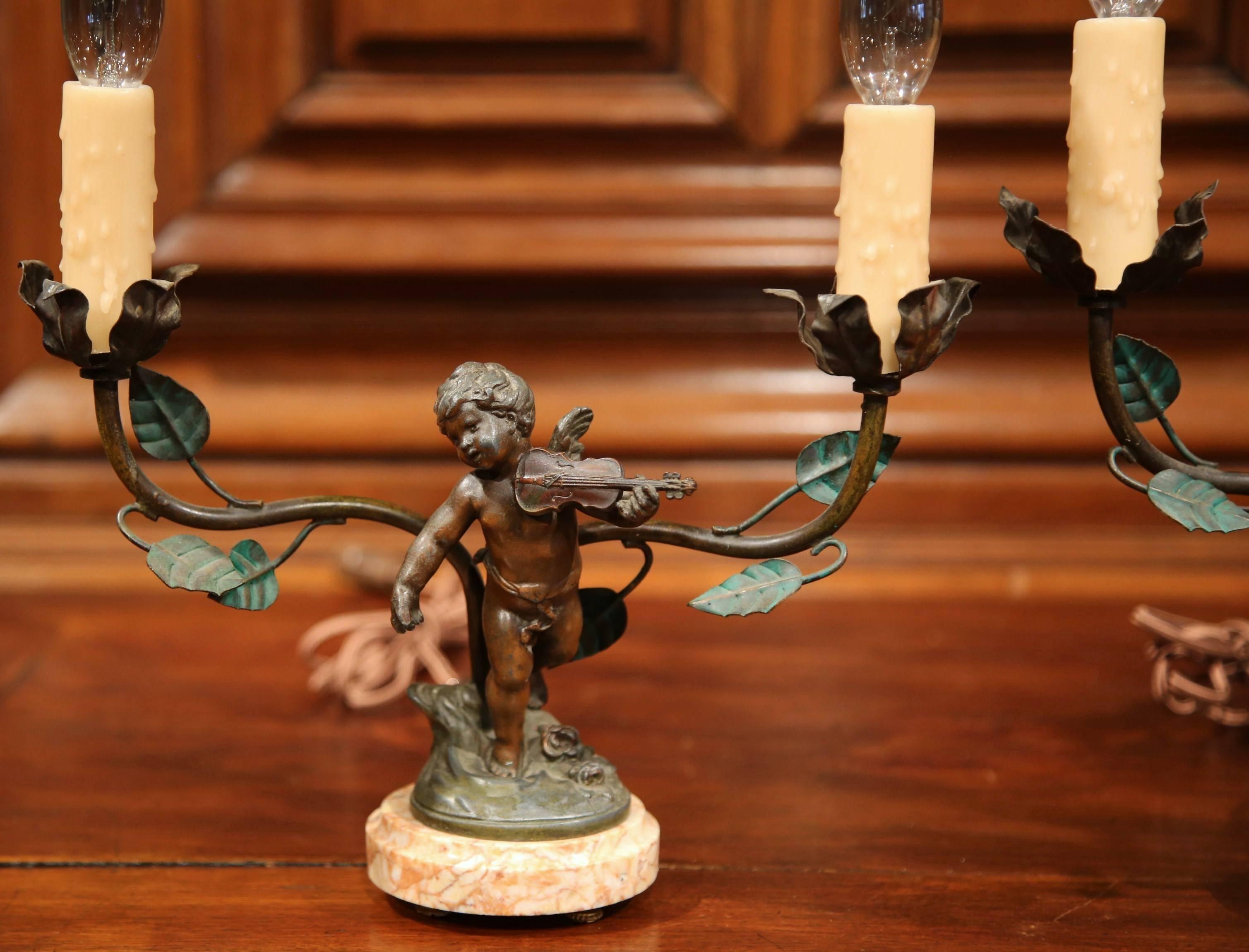This fine pair of antique table lamps were crafted in France, circa 1870. Each lamp features a patinated winged cherub with two lights covered with leaves. One of the base 