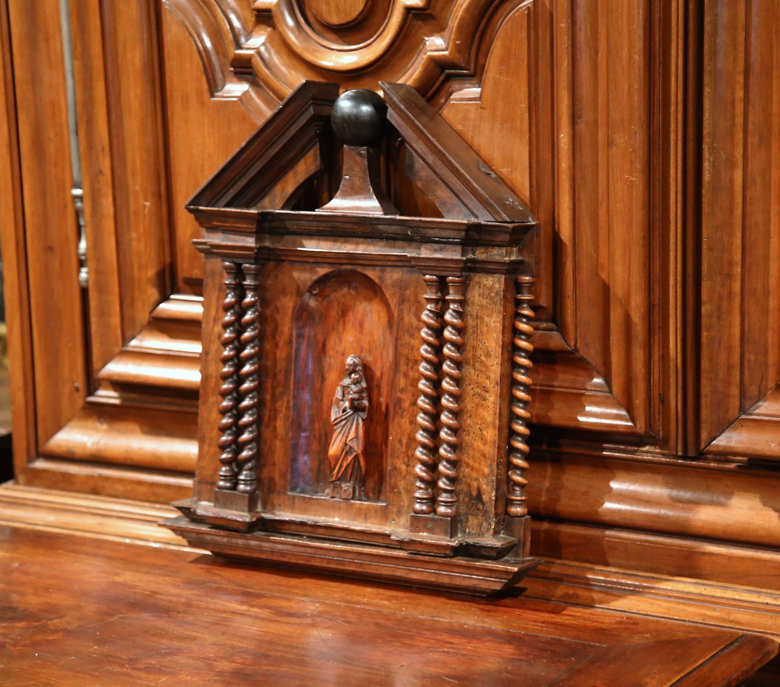 This elegant, fruitwood panel was carved in Southern France, circa 1740. The antique wall hanging religious plaque features the Virgin Mary holding Baby Jesus in the middle of a carved niche, flanked with six barley twist columns on the sides. The