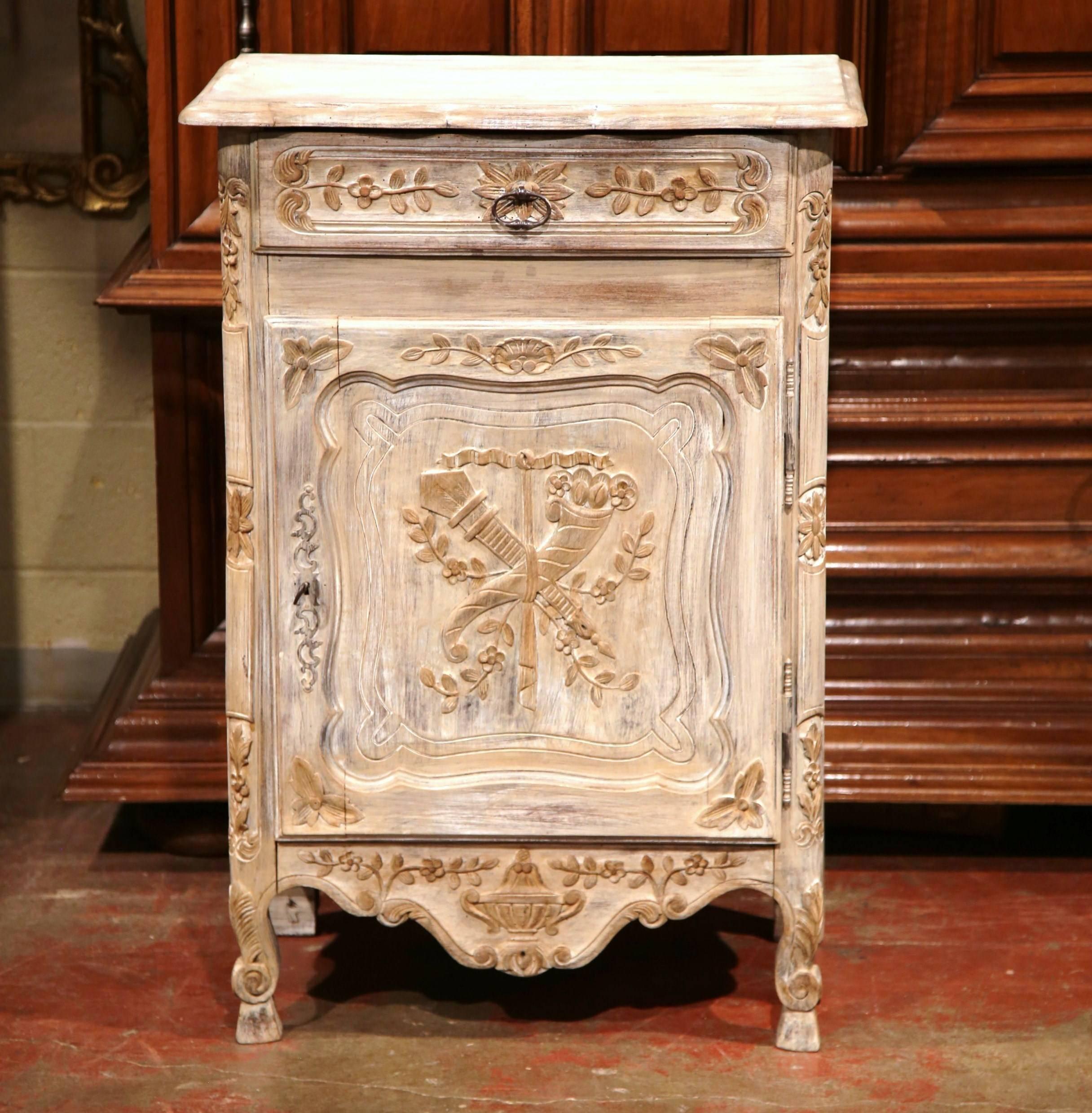 This elegant jelly cabinet was crafted in Northern France circa 1920. The heavily carved single door piece features delicate hand carvings on the front door and drawer with scrolled feet at the base. The confiturier is painted in a light bleached