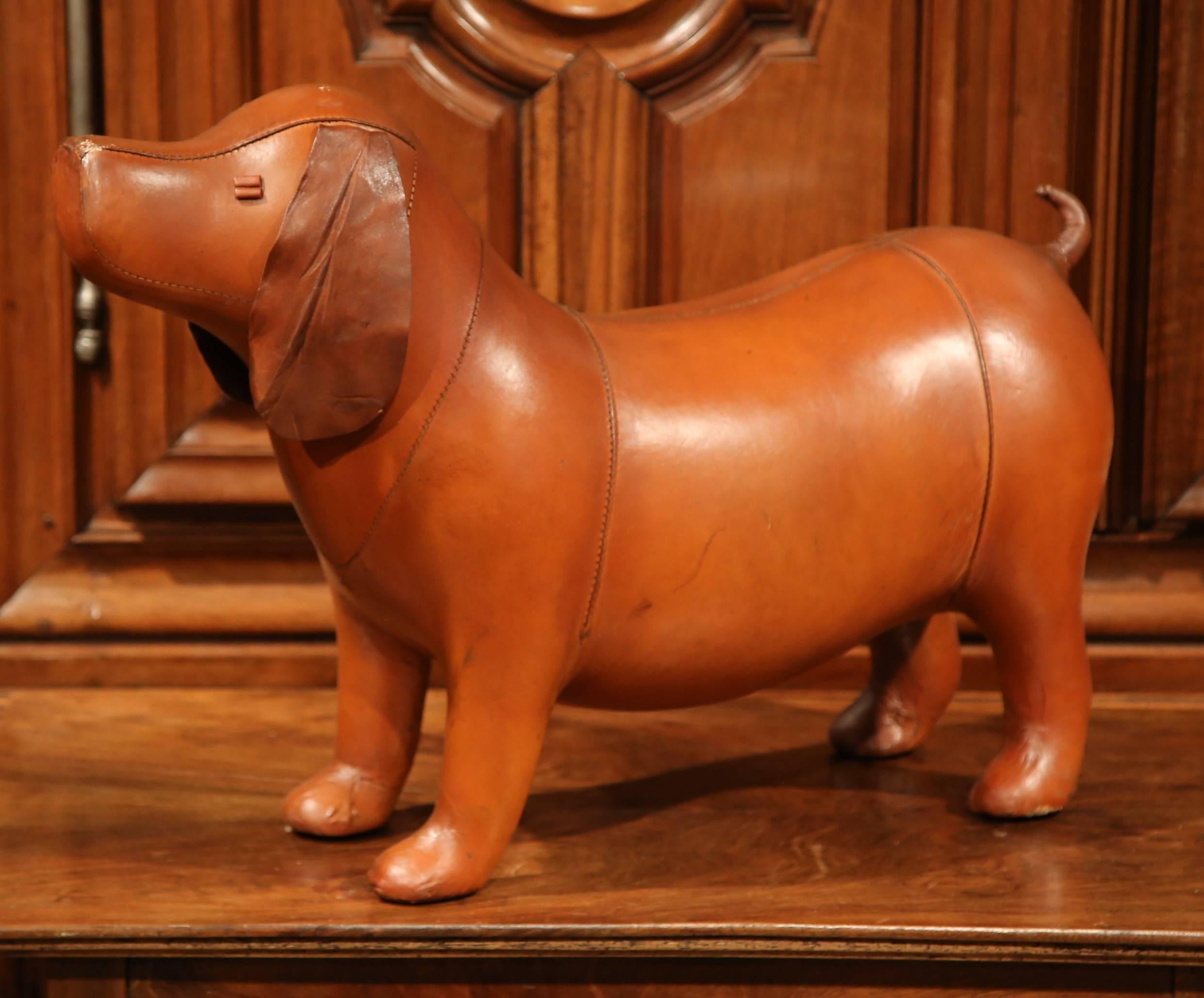 This unique leather footstool is full of character and will make a statement in your living room! Crafted in France, the footstool is in the shape of a dog and is covered in supple brown leather. The canine footrest has a curved back and is a