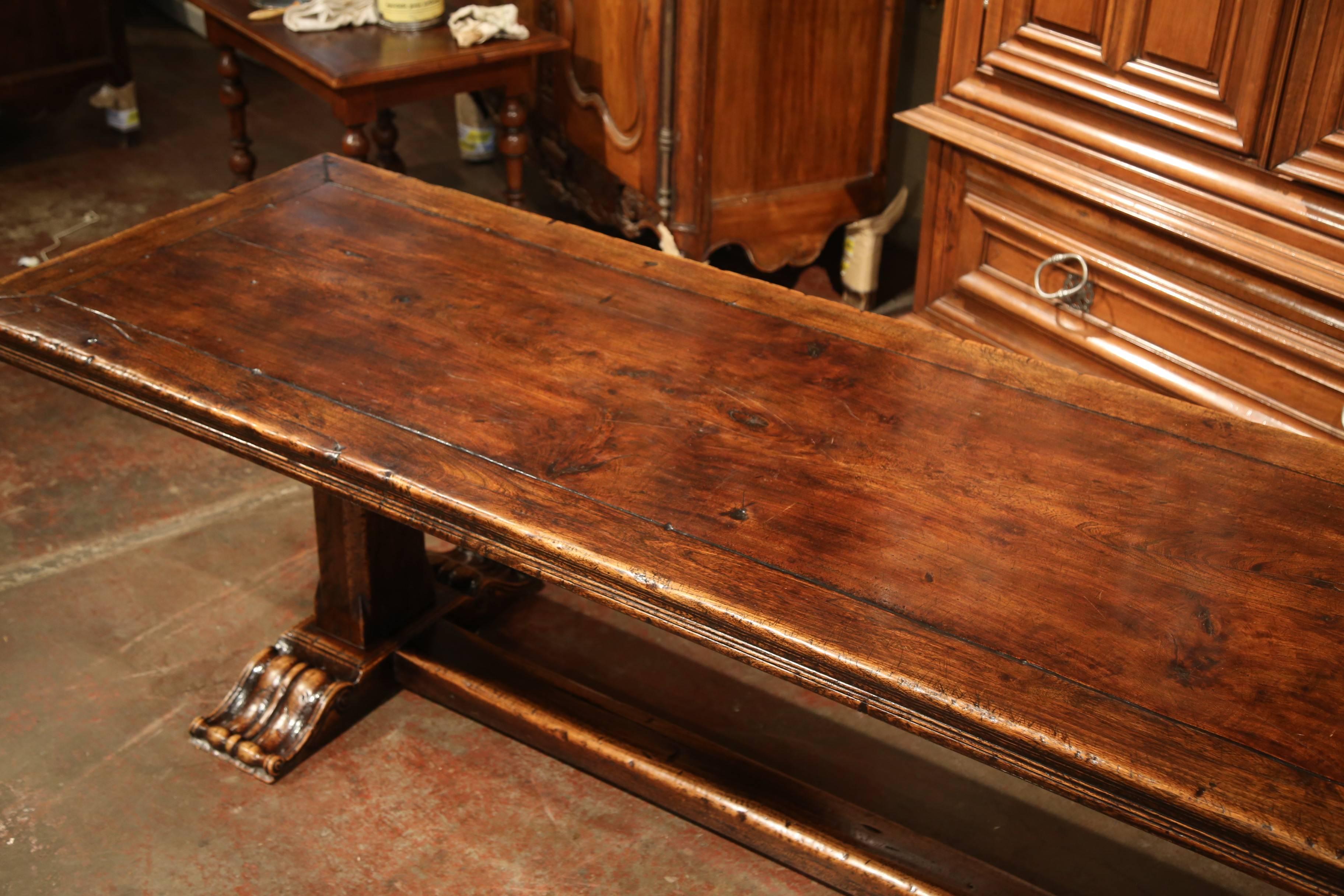 This large fruitwood dining room table was crafted in southwest France, near the Spanish and French border. The long tabletop features a walnut frame work around the center single plank surface, and embellished with carved edges around the