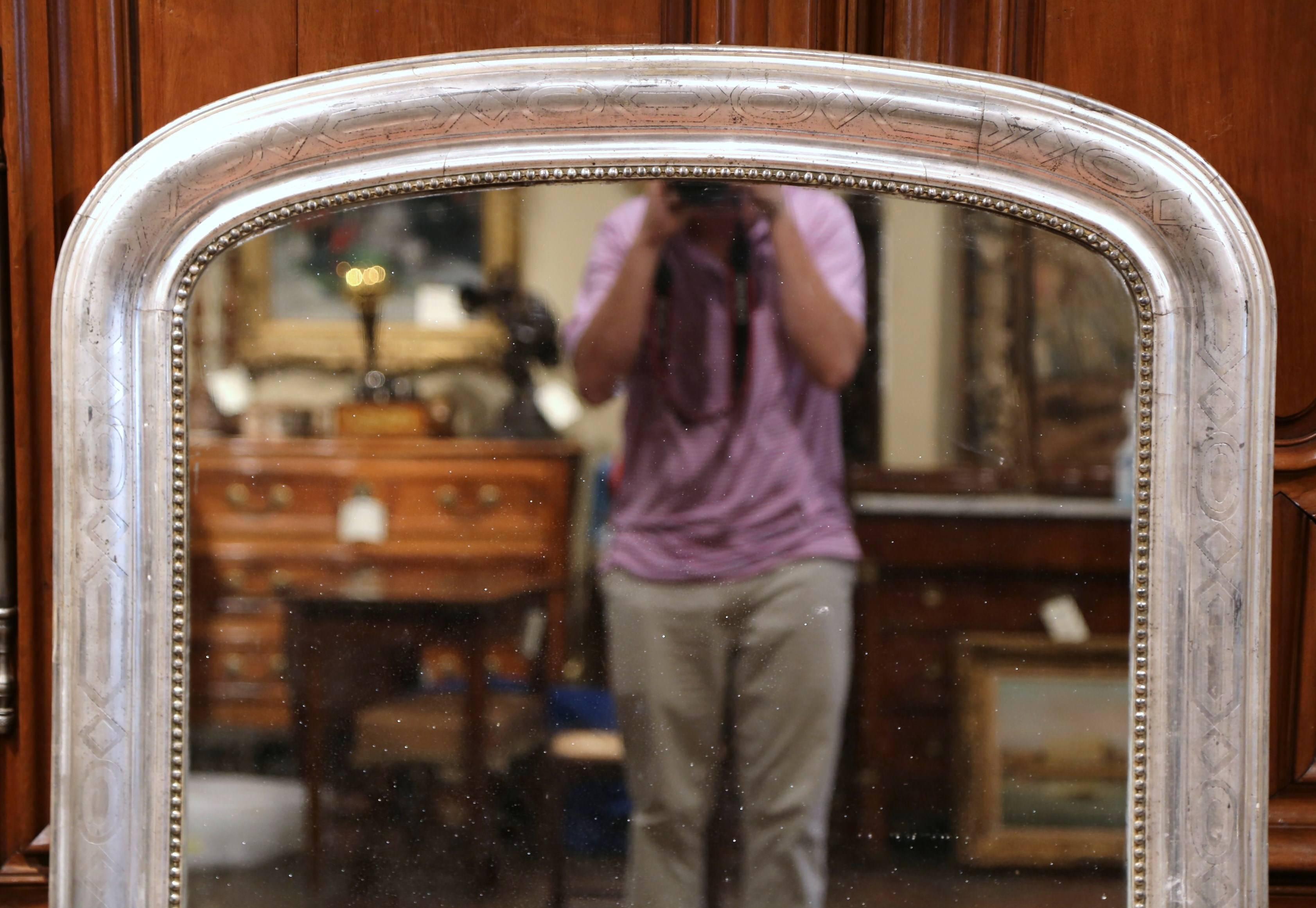 This elegant, tall antique mirror was crafted in France, circa 1860. The large rectangular wall hanging mirror with curved top, features some engraved Greek decorative design around the silver leaf frame. The traditional piece is in excellent