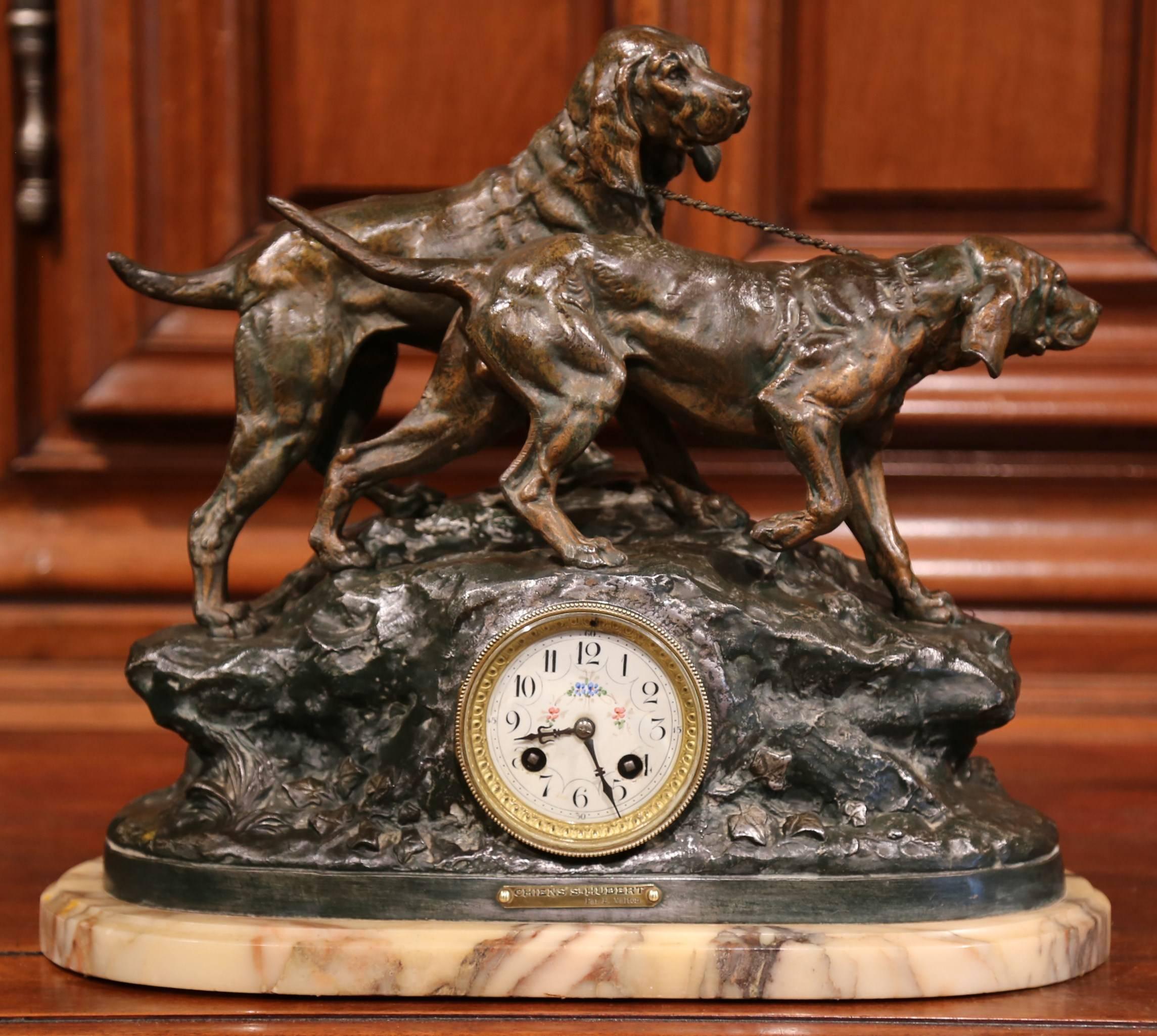 This beautiful mantel clock set was crafted in France, circa 1880. The centrepiece of this figural, spelter set has a clock on beige marble base with two hunting Saint Hubert dogs standing on rocky terrain above the centre face. The clock