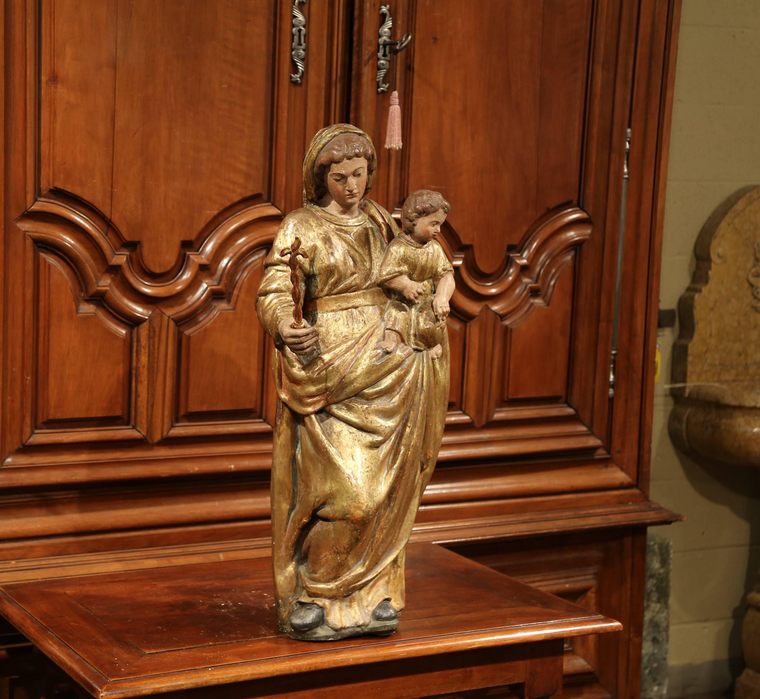 This beautiful antique statue of the Virgin Mary with baby Jesus was carved in France, circa 1750. The alluring polychrome and gilt high relief sculpture features Madonna carrying her Child. The tall religious figure has wonderful detailed carving