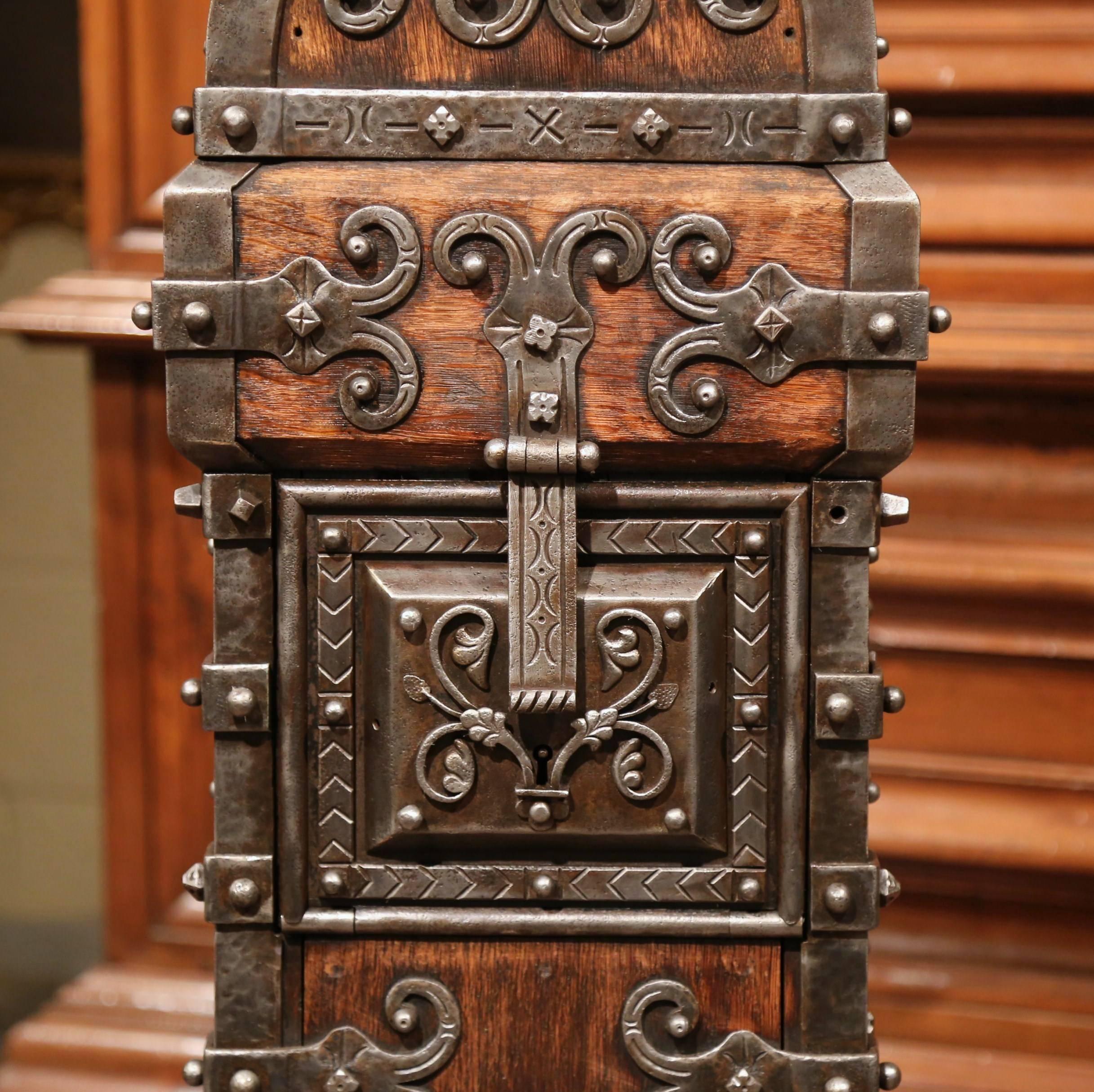 This elegant antique safe was forged and carved in Spain, circa 1750. The tall polished iron and wood church trunk features a curved top with a slot for money, and a triple lock with two keys, which allows you to access the inside removable metal