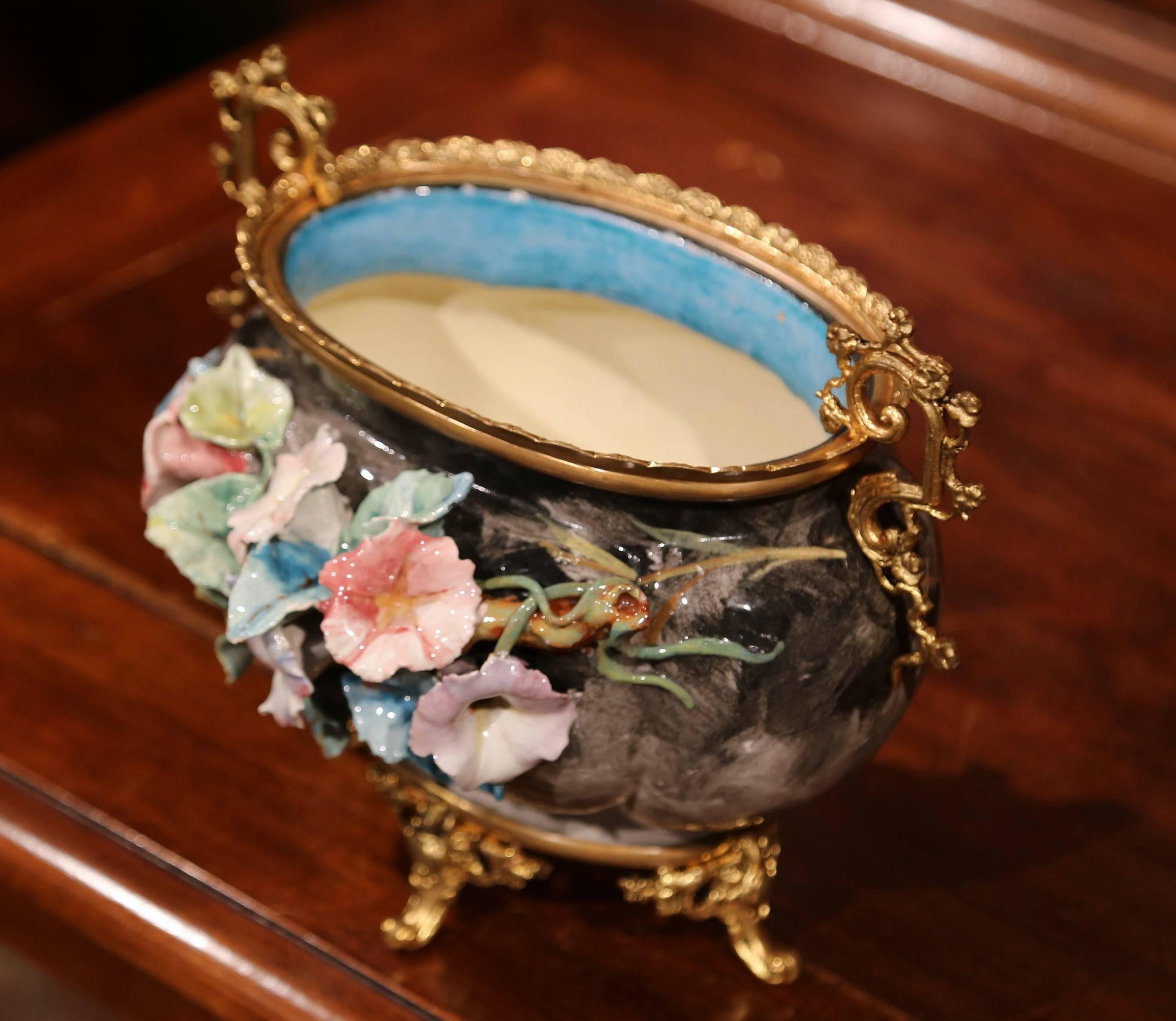 Embellish your home with this elegant antique, hand-painted Majolica planter from Montigny sur Loing, France. Sculpted, circa 1860, the ornate jardinière sit on a bronze base with four ornate scrolled feet and features colorful hand painted flowers