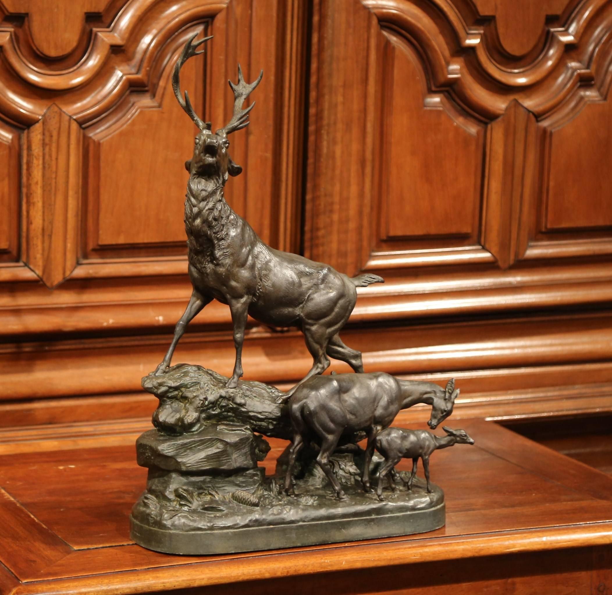 This beautiful, antique, patinated metal composition was sculpted in France, circa 1880. The tall detailed spelter sculpture features a realistic deer family with a buck at bay standing on top of a rocky terrain and a doe attending her young fawn.