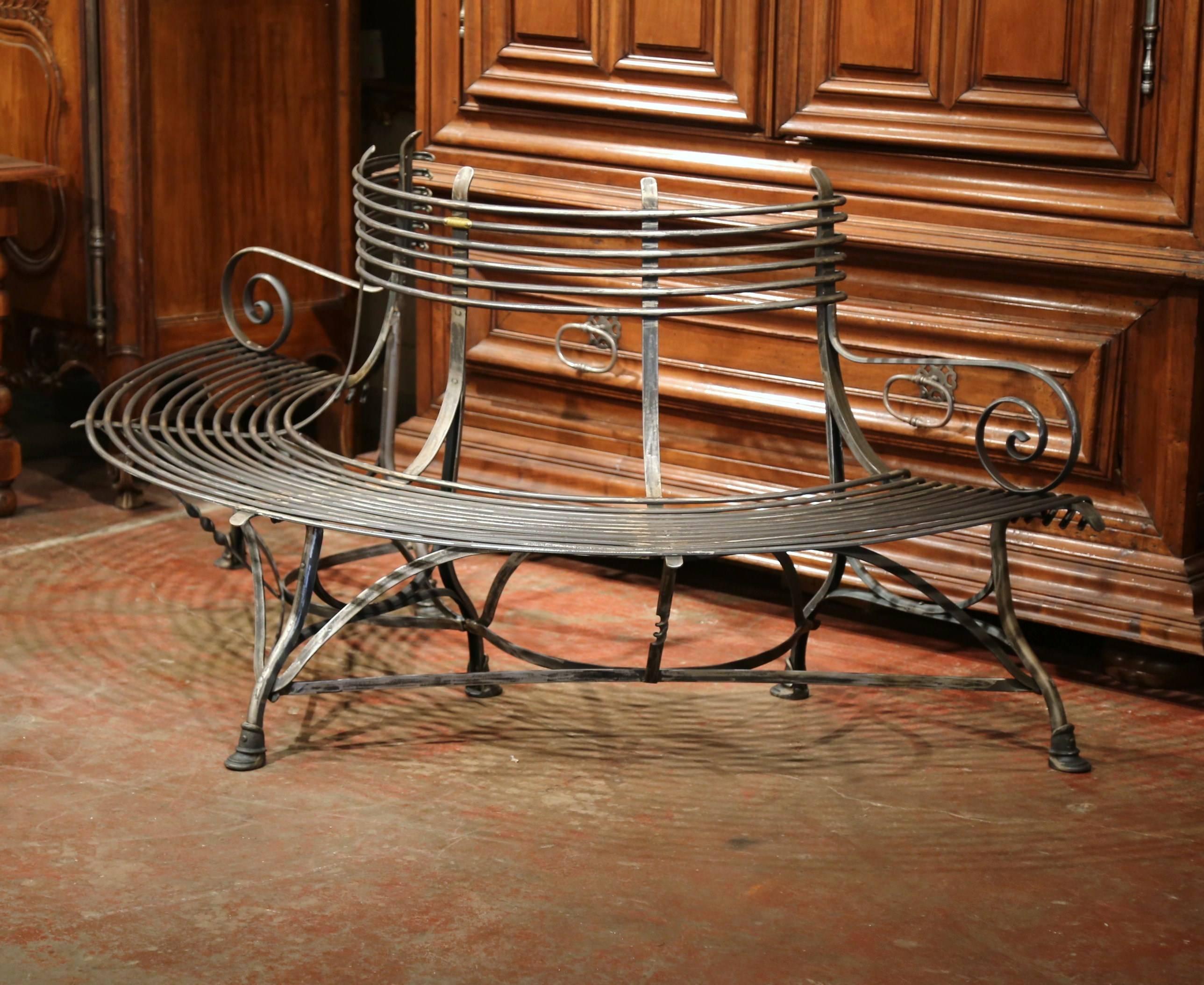This elegant, curved iron bench was created in France. This durable bench is shaped so that it could wrap around a tree, and has scrolled armrests on both sides and hoof feet at the bottom. The bench has a polished gun barrel finish with a plaque on