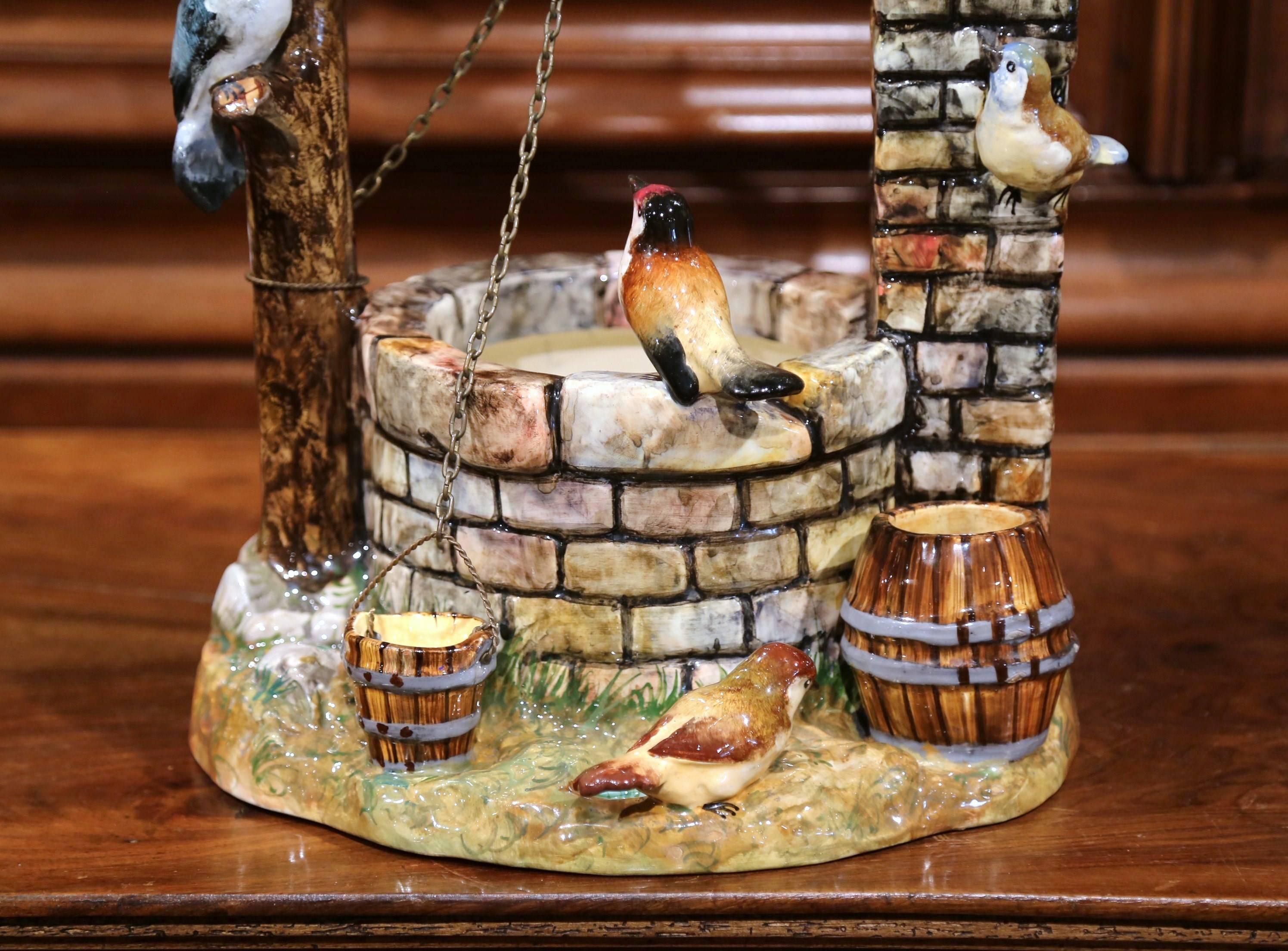 This large and colorful antique Majolica composition was sculpted in Southern France, circa 1890. The hand painted, multi-color faience jardinière features seven birds and a couple of buckets around a well; one of the buckets is tied to the well's