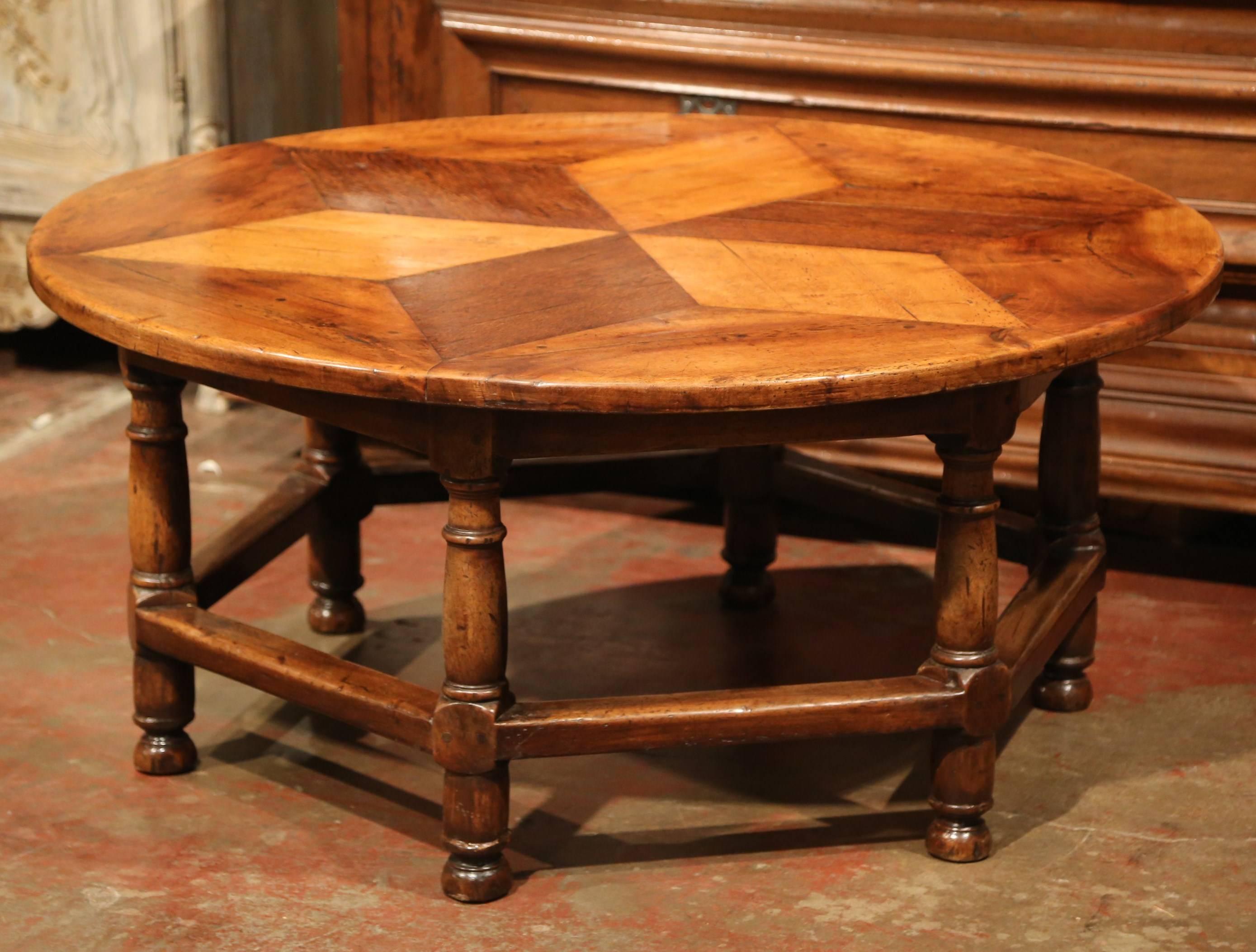 This elegant cocktail table was crafted in Southern France, circa 1970. The traditional, round coffee table features six turned legs with a hexagonal stretcher in between. The top is embellished with a geometric parquet design top. The surface is a