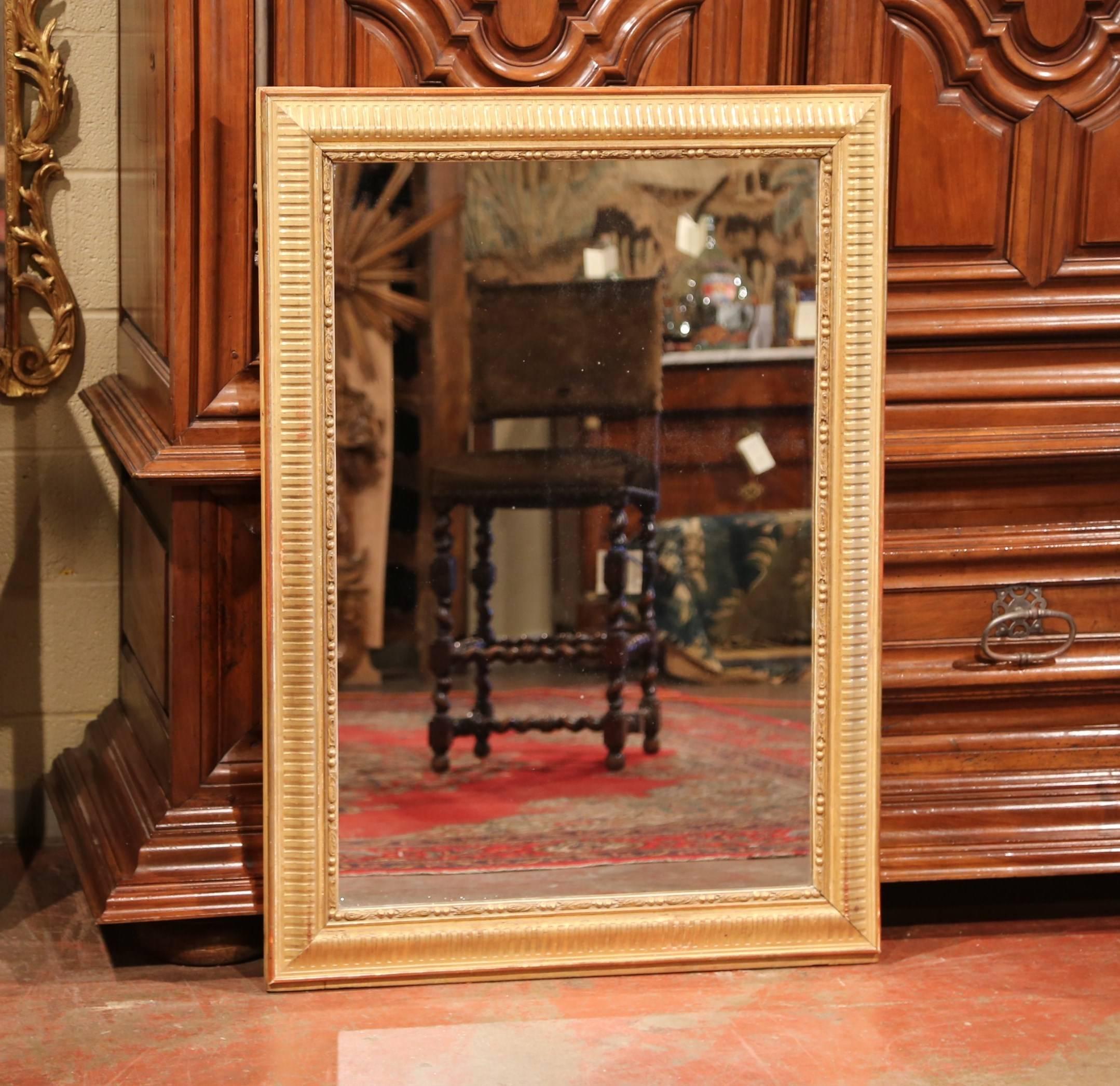 This elegant, antique wall mirror was crafted in Paris, France, circa 1860. The large, rectangular, carved wooden frame is embellished with gold leaf stripe motifs, and can be hung either vertically or horizontally. The Louis XVI classic frame has