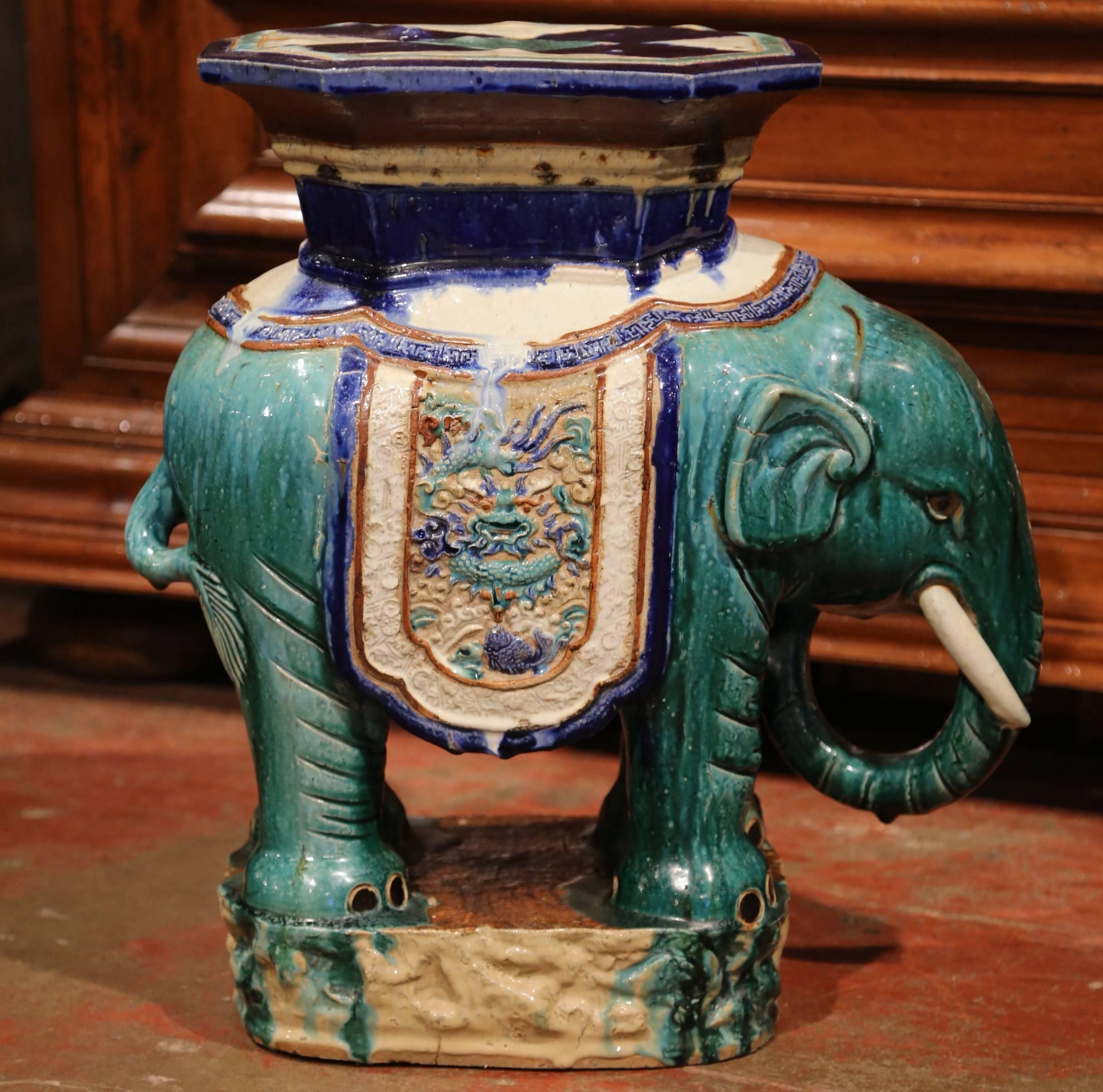 This colorful porcelain garden seat was sculpted in France, circa 1920. The shaped elephant features heavy decorated oriental finery. The mammal has a hexagonal seat at the top and is hand painted in the green, blue and beige palette. This unique