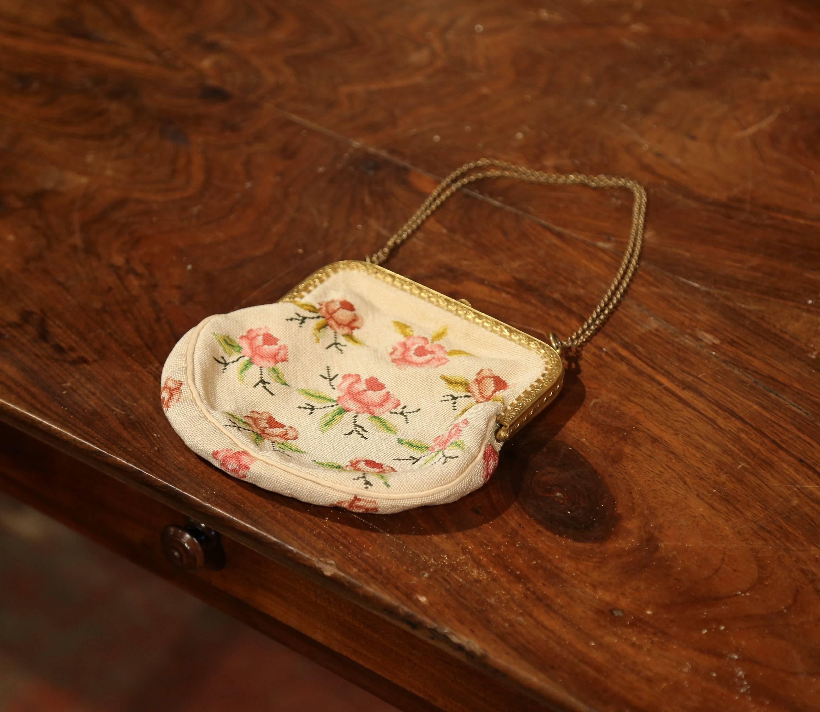 Elegant antique purse from France; handwoven circa 1860, the small colorful purse is handmade using needlepoint technique. It features pink roses with green leaves on both sides. It is further embellished with a brass shoulder strap and brass