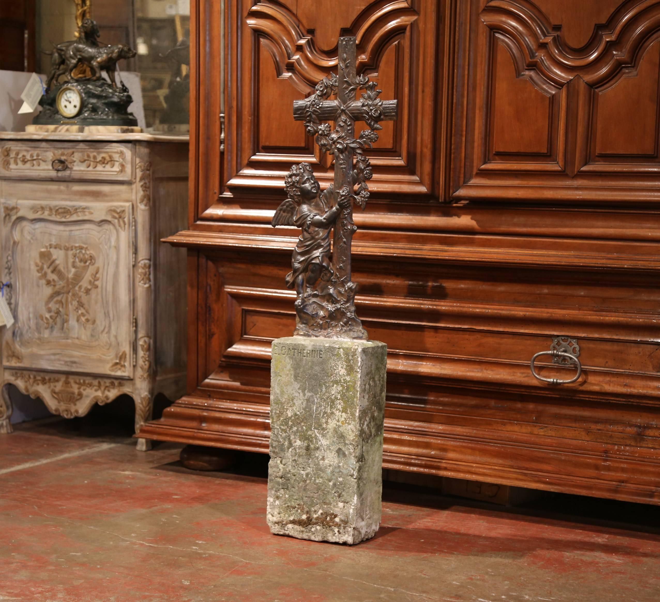 This elegant, antique cross was crafted in Southern France, circa 1850. The unique, sturdy garden piece features a cross with a cherub standing beside it. The cross is wrapped up with a lush crown of flowers and foliage. The base is made of a block