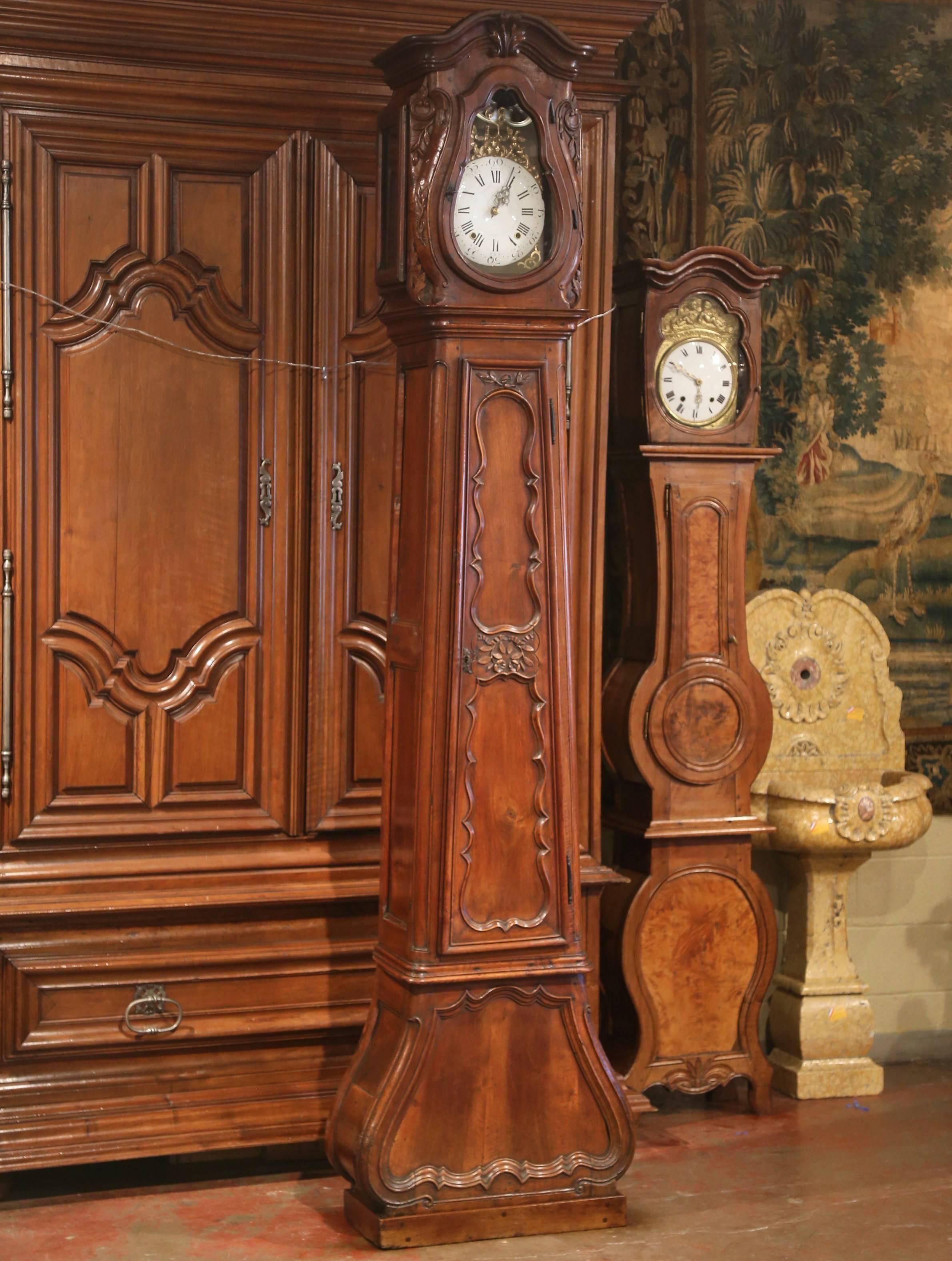 This elegant, antique long case clock was crafted in Lyon, France, circa 1760. The tall fruitwood grandfather clock features beautiful carved lines with a bonnet top, flowers and leaves on the doors and a bowed base. The clock mechanism has been