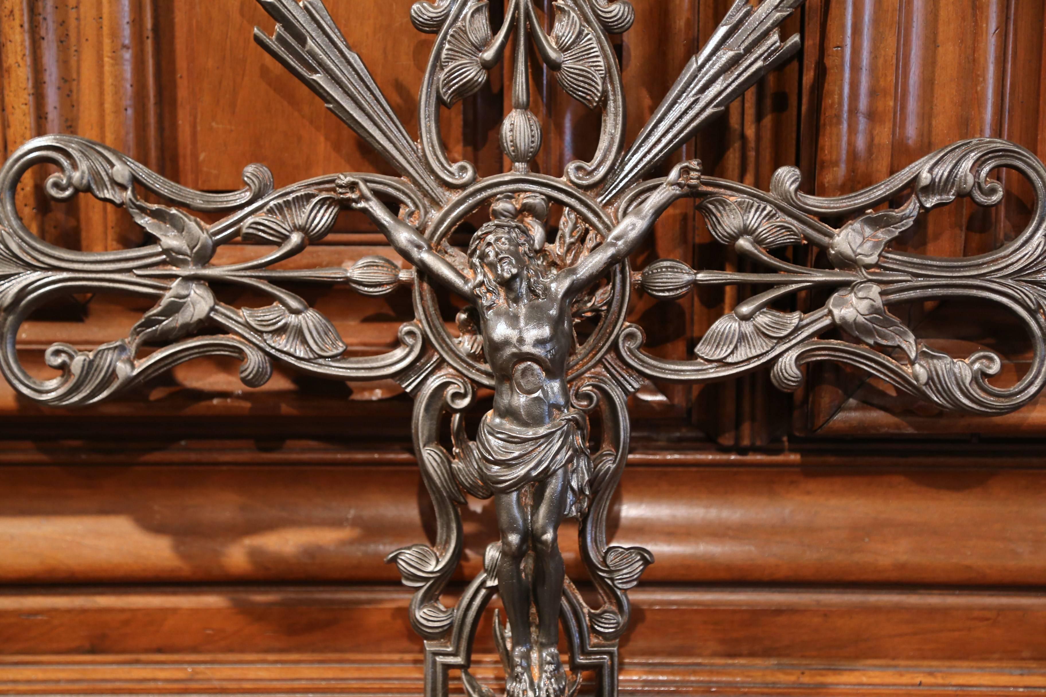 This beautiful, antique crucifix was crafted in France, circa 1860. The large iron piece features our Lord Jesus Christ nailed to the cross embellished with flowers and leaves. The classic crucifix sculpture has its original polished patinated