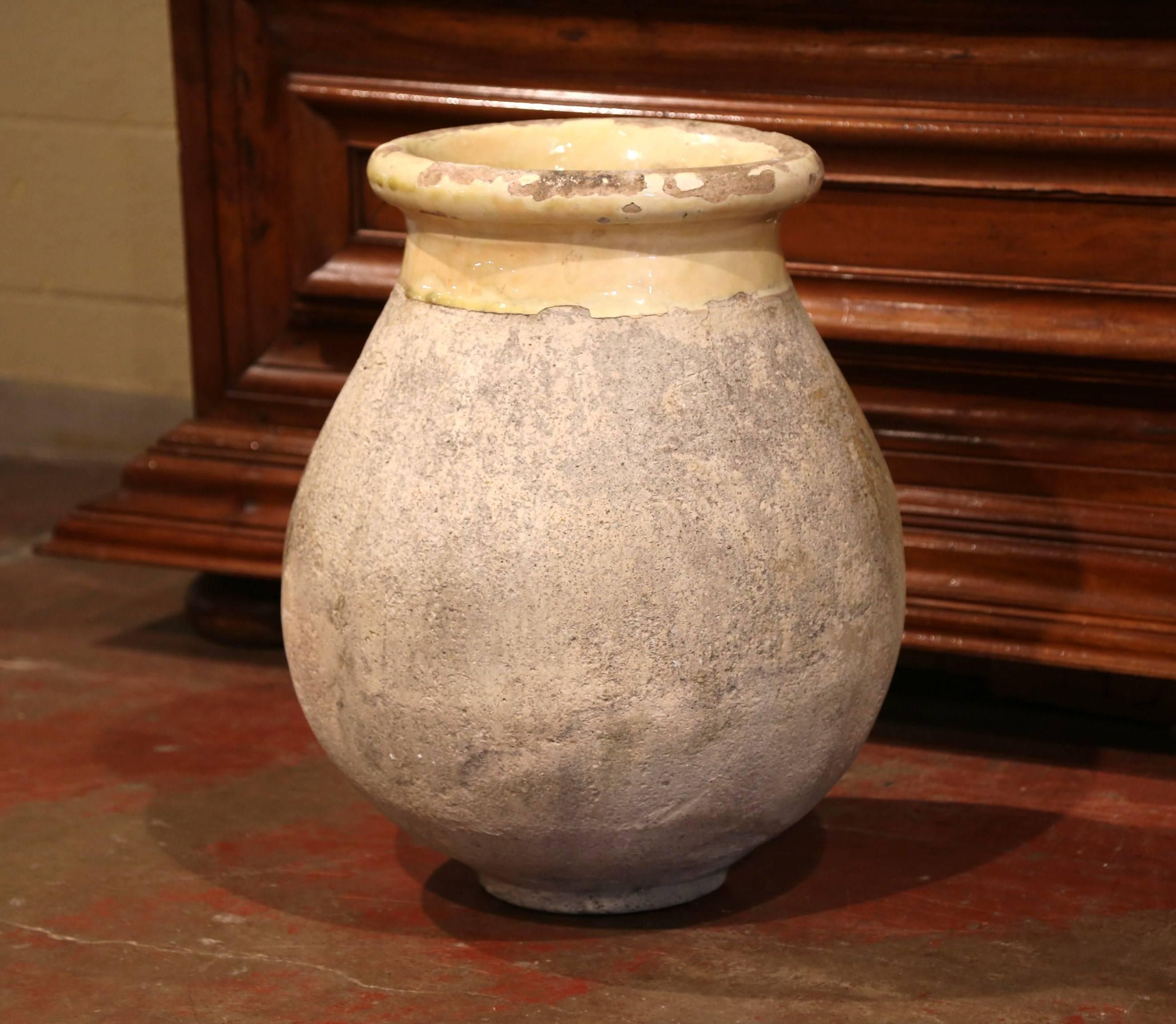 This beautiful, antique earthenware olive jar was created in Southern France, circa 1870. Made of blond clay and neutral in color, the terracotta has a traditional round shape; the pot features a yellow glaze around the neck and trim, and a natural