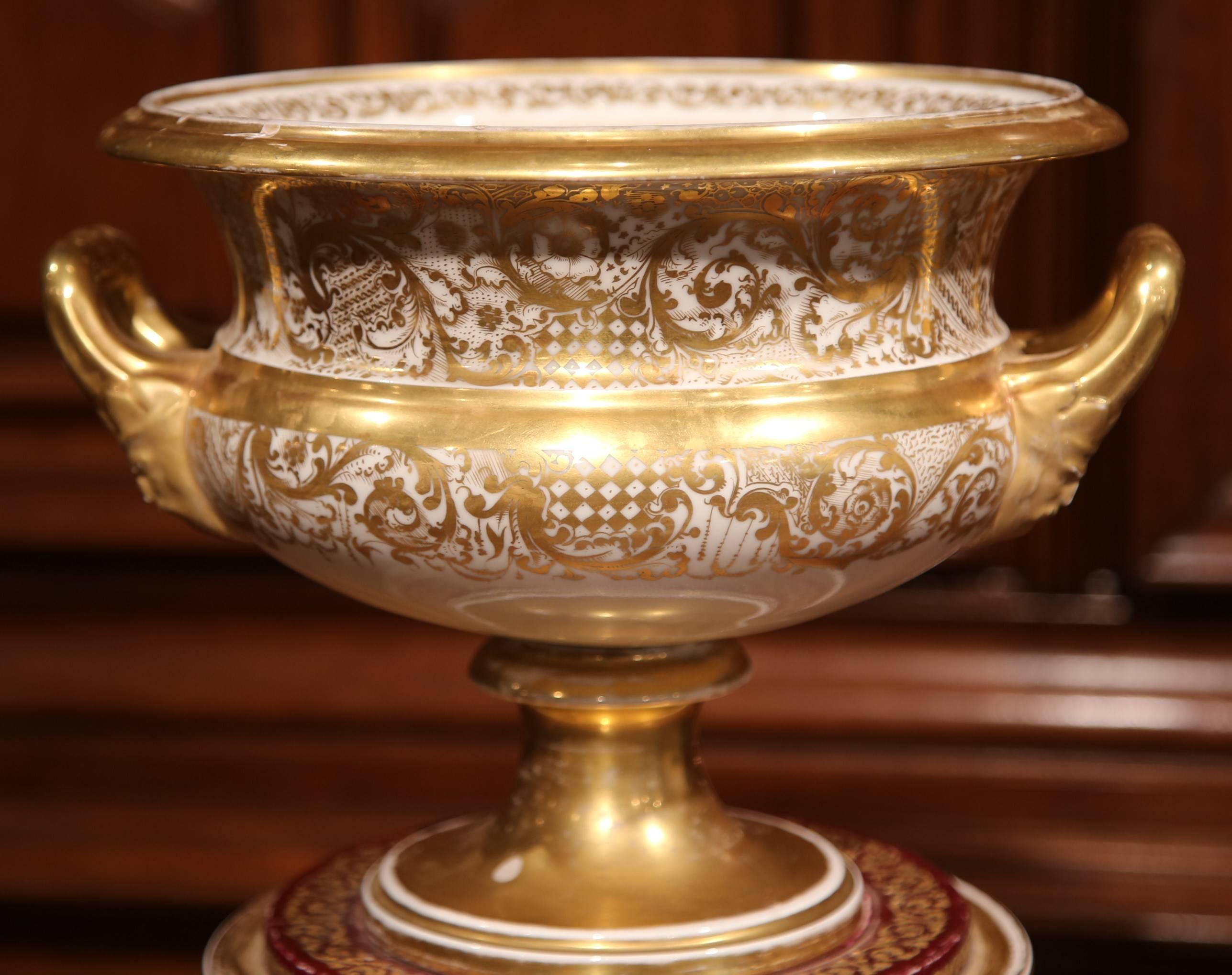 This elegant, antique, hand-painted porcelain cache pot was crafted in Paris, France, circa 1870. The vase has a gilt finish, small handles and a round decorative base with hand-painted fruits, flowers and butterfly motifs. The unique urn is in