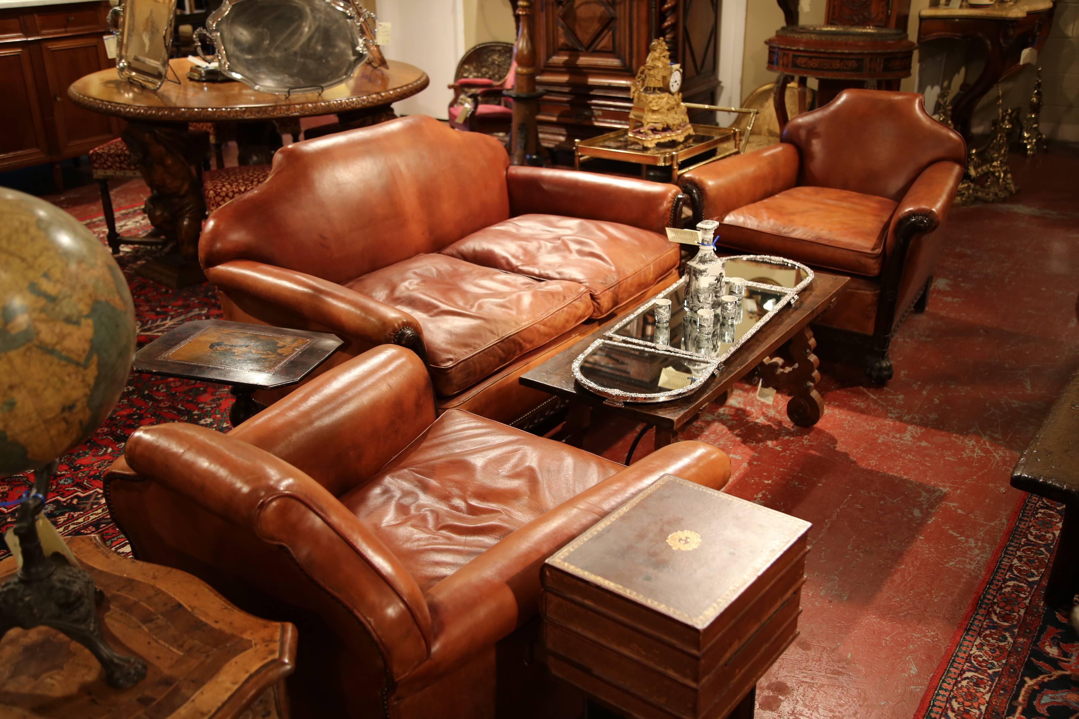 Add comfort, beauty and charm to your living room or study with this exquisite set of antique leather salon seating. Crafted in England, circa 1890, this set includes a sofa and a pair of matching armchairs. All three pieces are covered with