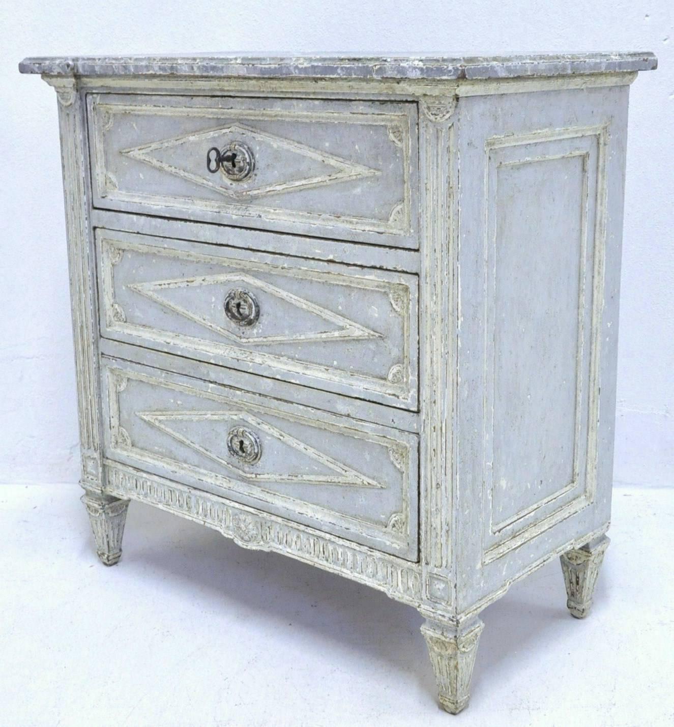 Add extra surface space and storage to your bedroom with this pair of Louis XVI style antique painted bedside tables crafted in France, circa 1870. The two nightstands chests both have a faux marble top in a neutral gray tone and feature three