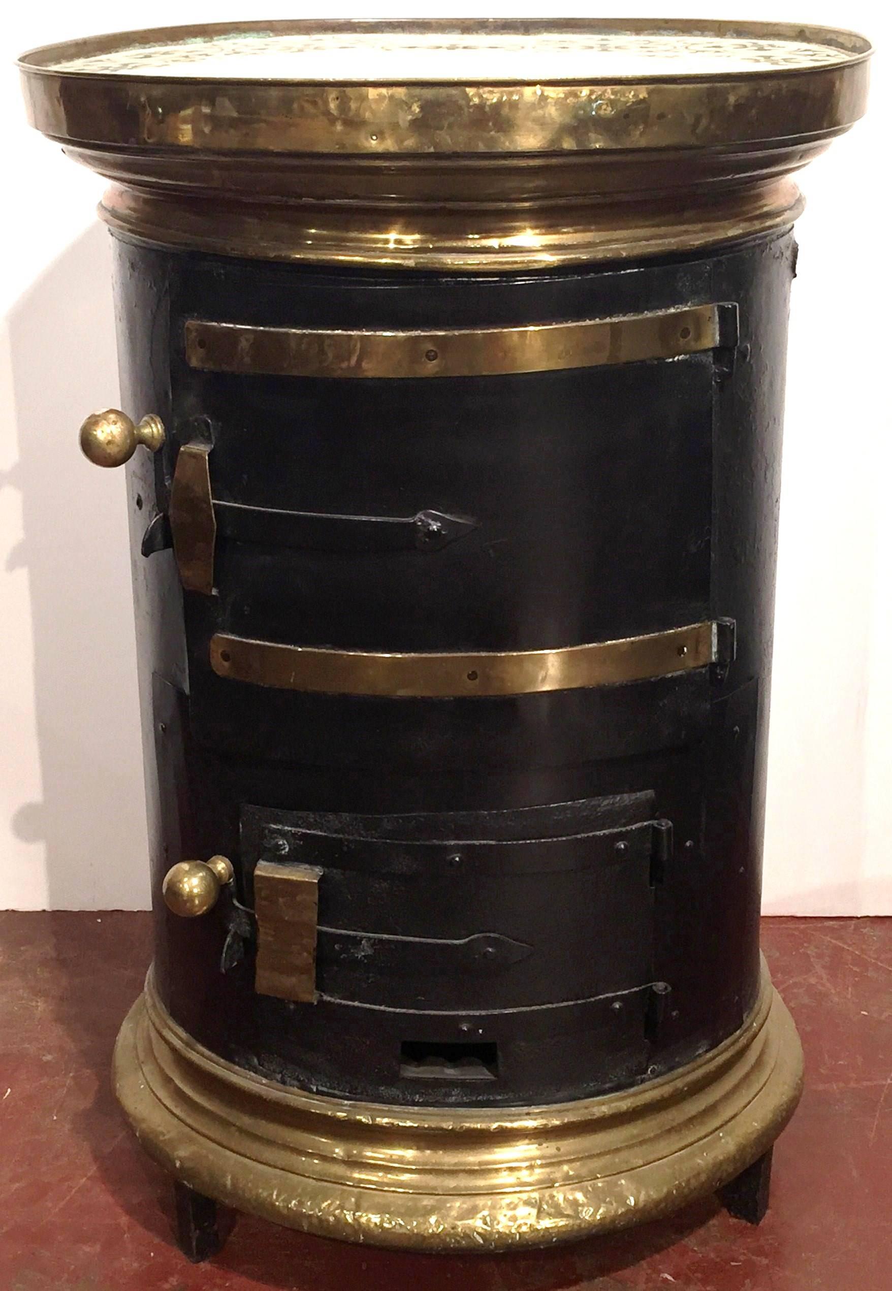 This interesting iron and brass heater was created in Versailles, France, circa 1870. The antique, circular warmer features copper rings at base, two doors with brass knobs and a brass ring at the top embellished by hand painted tiles on the