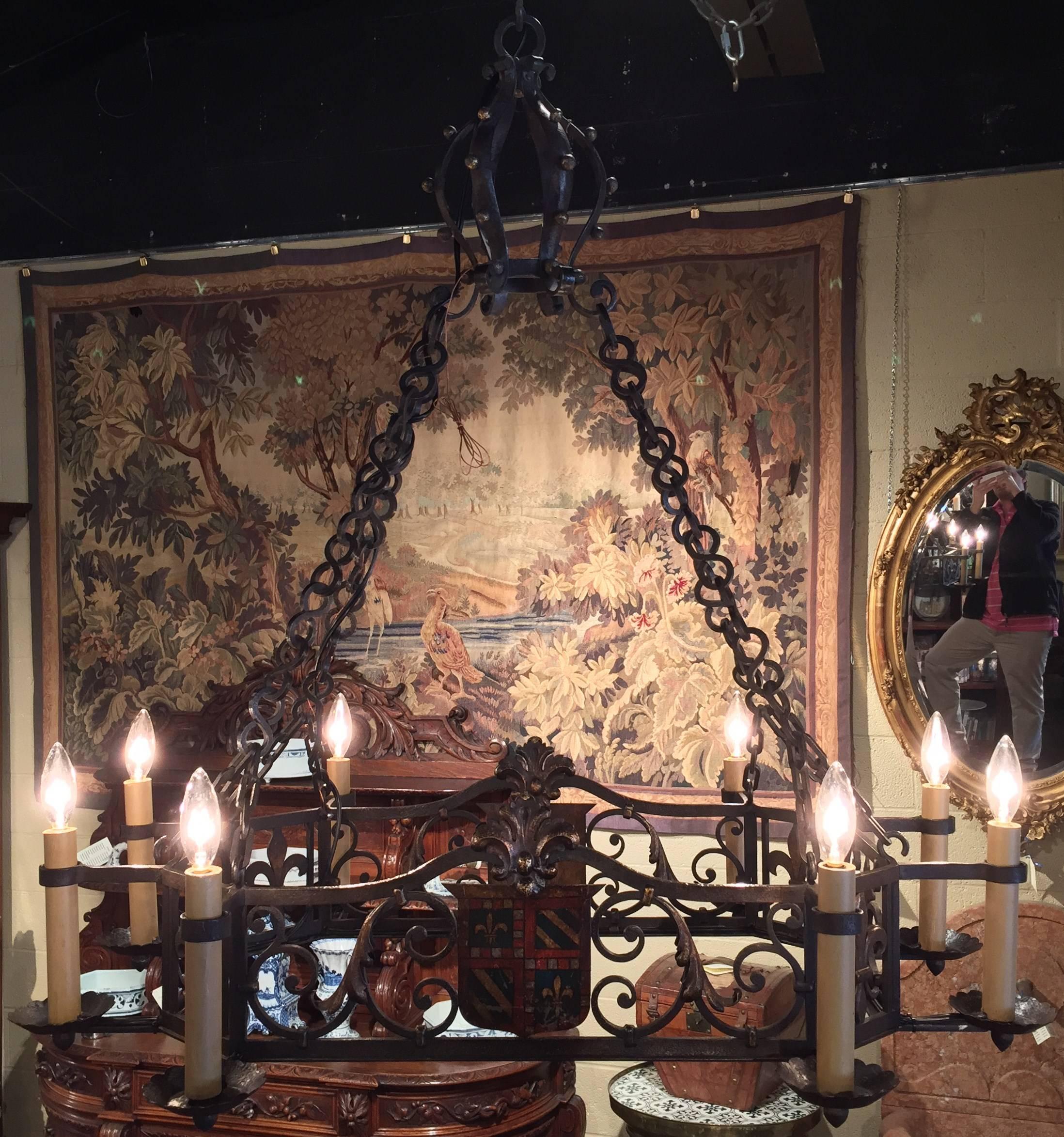 19th century iron chandelier with eight lights, circa 1870. Featuring  2 painted coat of arms with Fleur de Lys. Rewired, it also has the eight original wood candles.