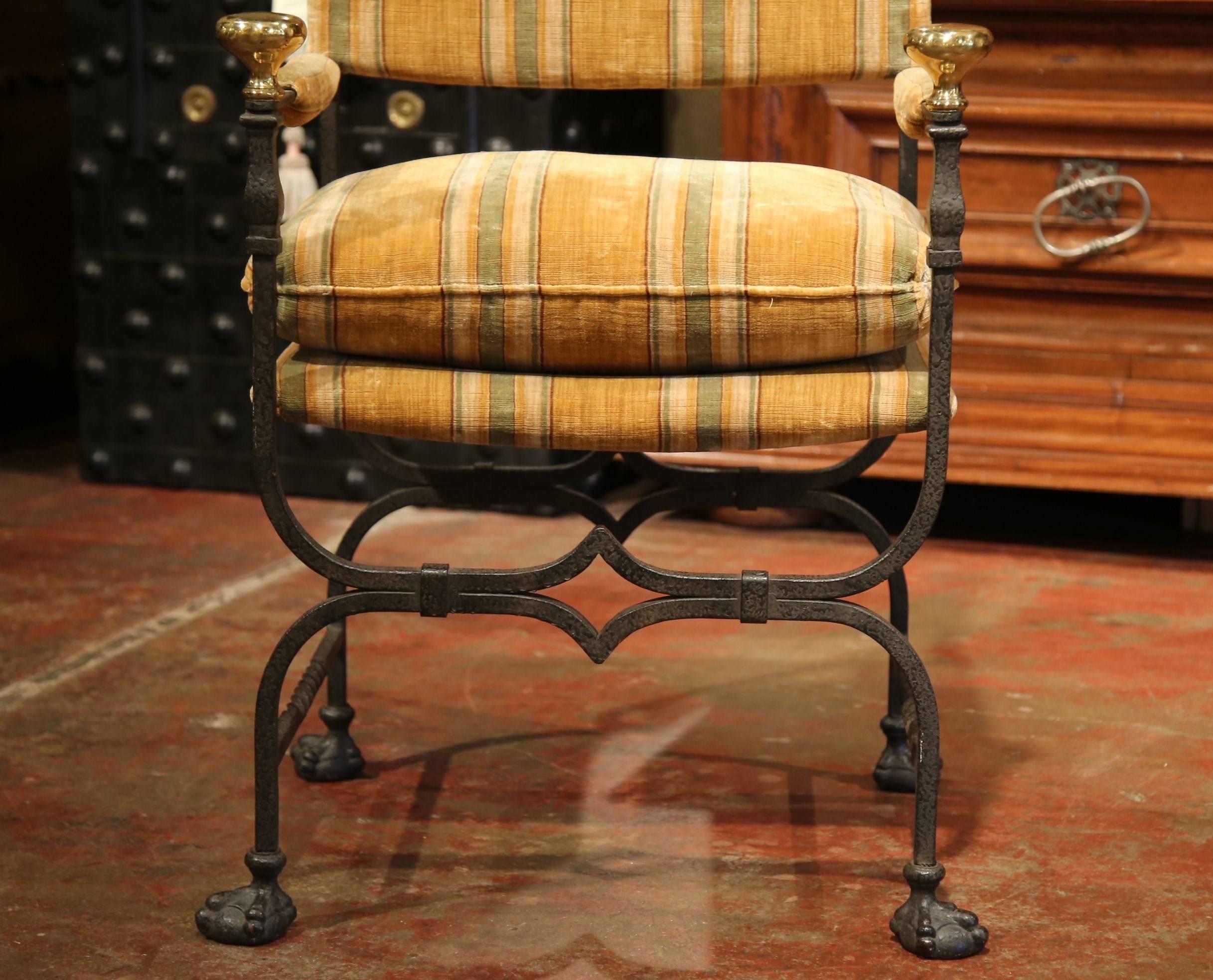 This elegant, antique Campaign armchair was created in Italy, circa 1880. The frame of the chair is formed from forged iron. The piece has scrolled legs, bronze rosette finials, and the seat is upholstered with a striped gold velvet fabric.