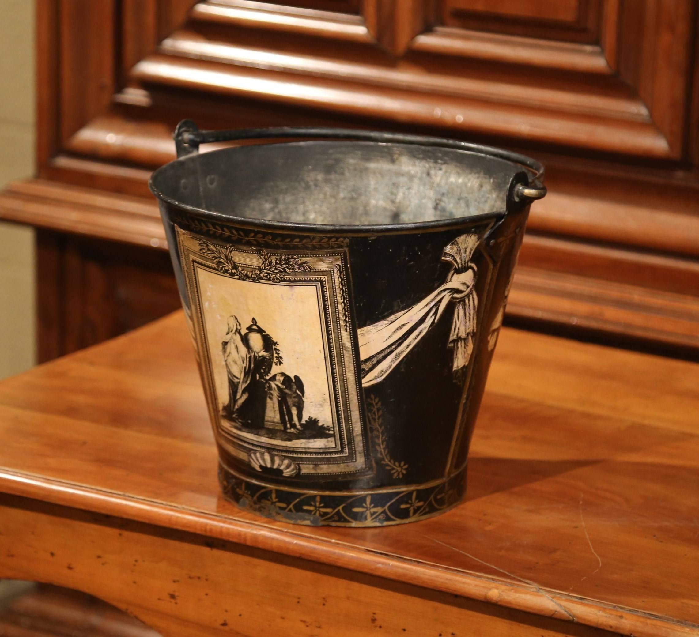 Crafted in Paris, circa 1860, the elegant antique bucket with iron handle, features hand painted mythological scenes on both sides embellished with garland and swag decor. The round basket is in excellent condition with a rich patinated black and