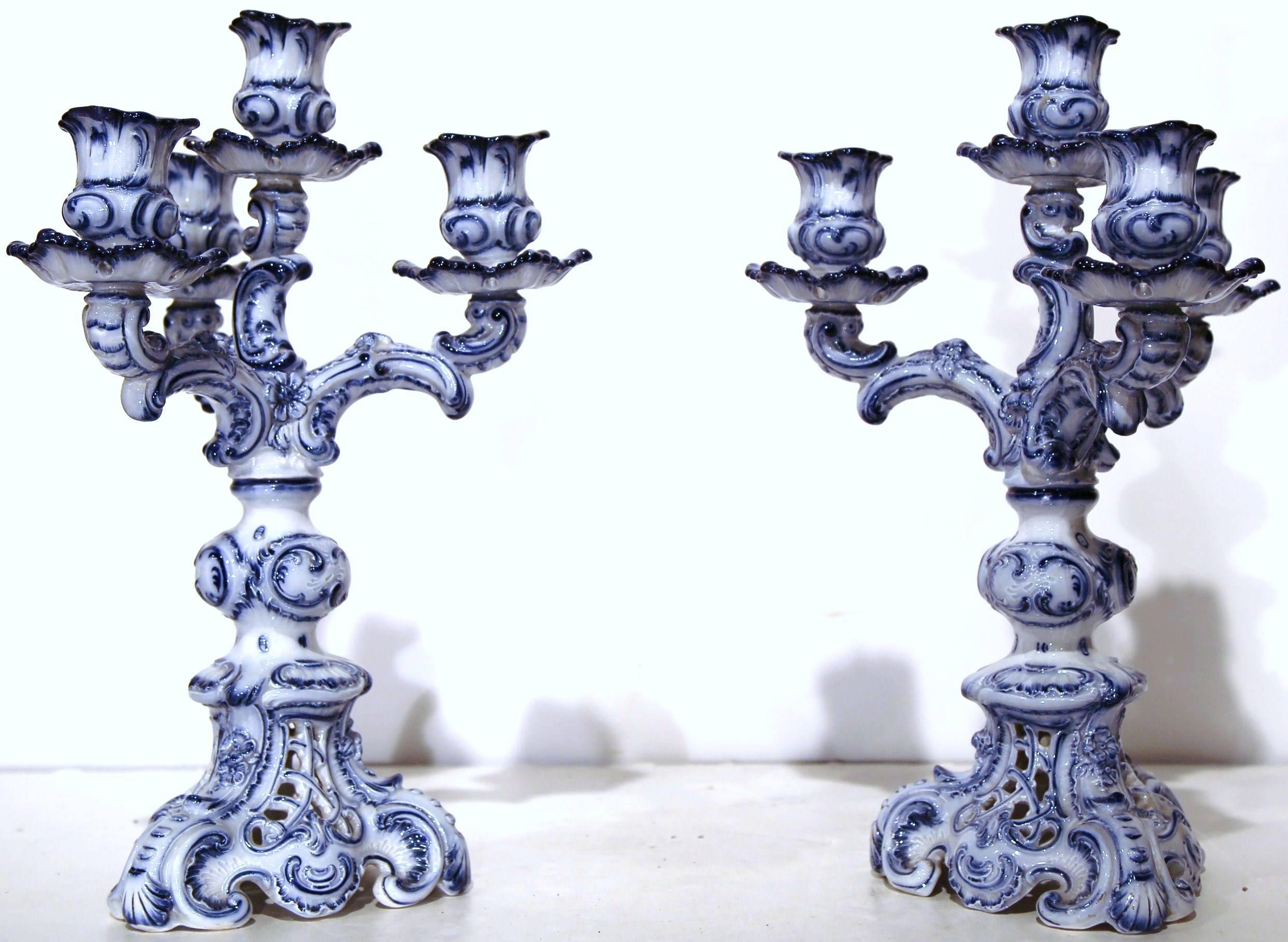 Decorate a table or mantel with this Classic pair of porcelain candleholders. Sculpted in France, circa 1920, the antique candelabras stand on small scroll feet, with three outside arms and one elevated in the center. Traditional and blending with