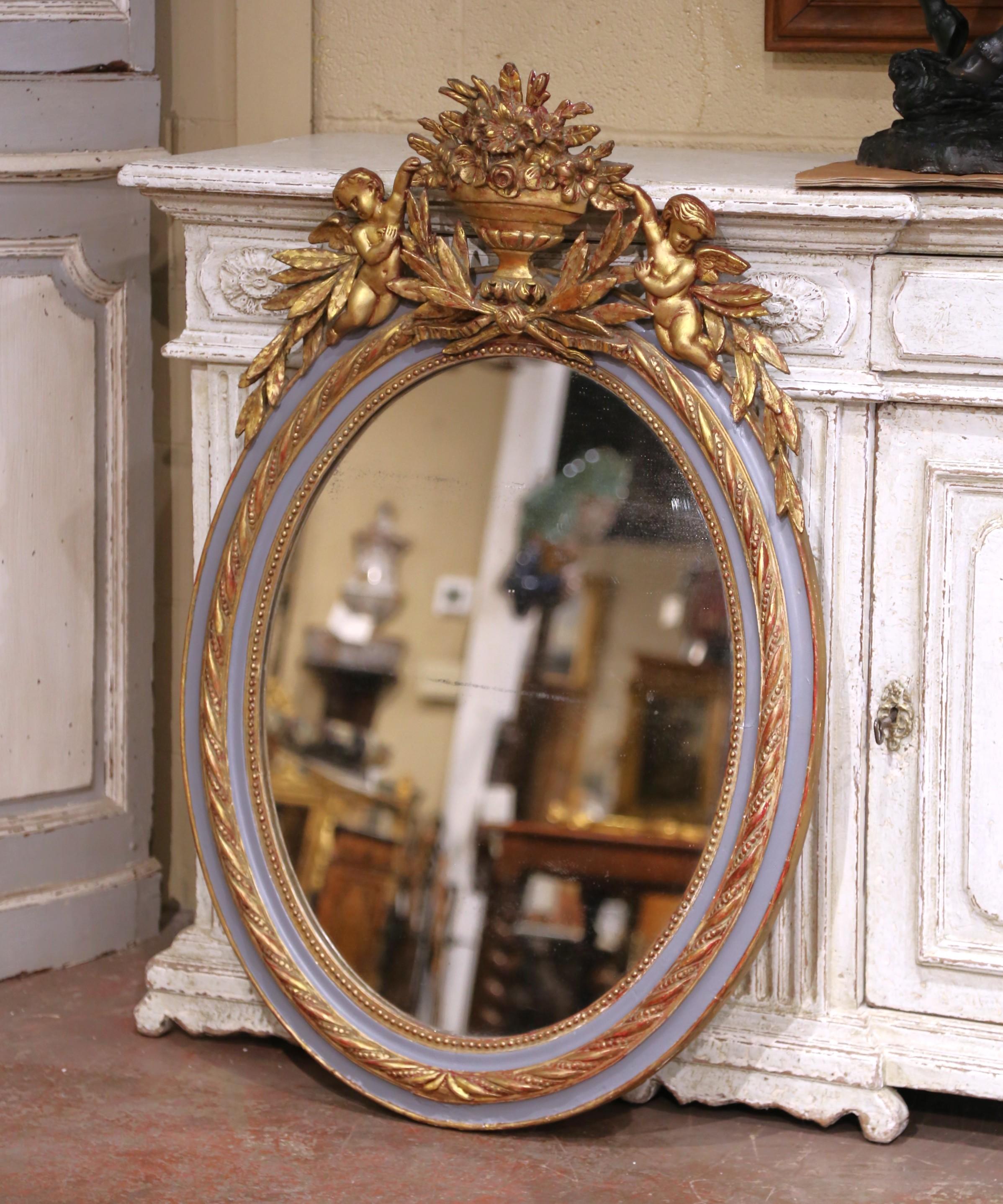 Décorez une entrée, un salon ou une salle d'eau avec cet élégant miroir mural français ancien. Fabriqué vers 1870, le cadre ovale est sculpté dans le bois et fini dans une palette bicolore raffinée, combinant une douce peinture bleu ardoise avec des