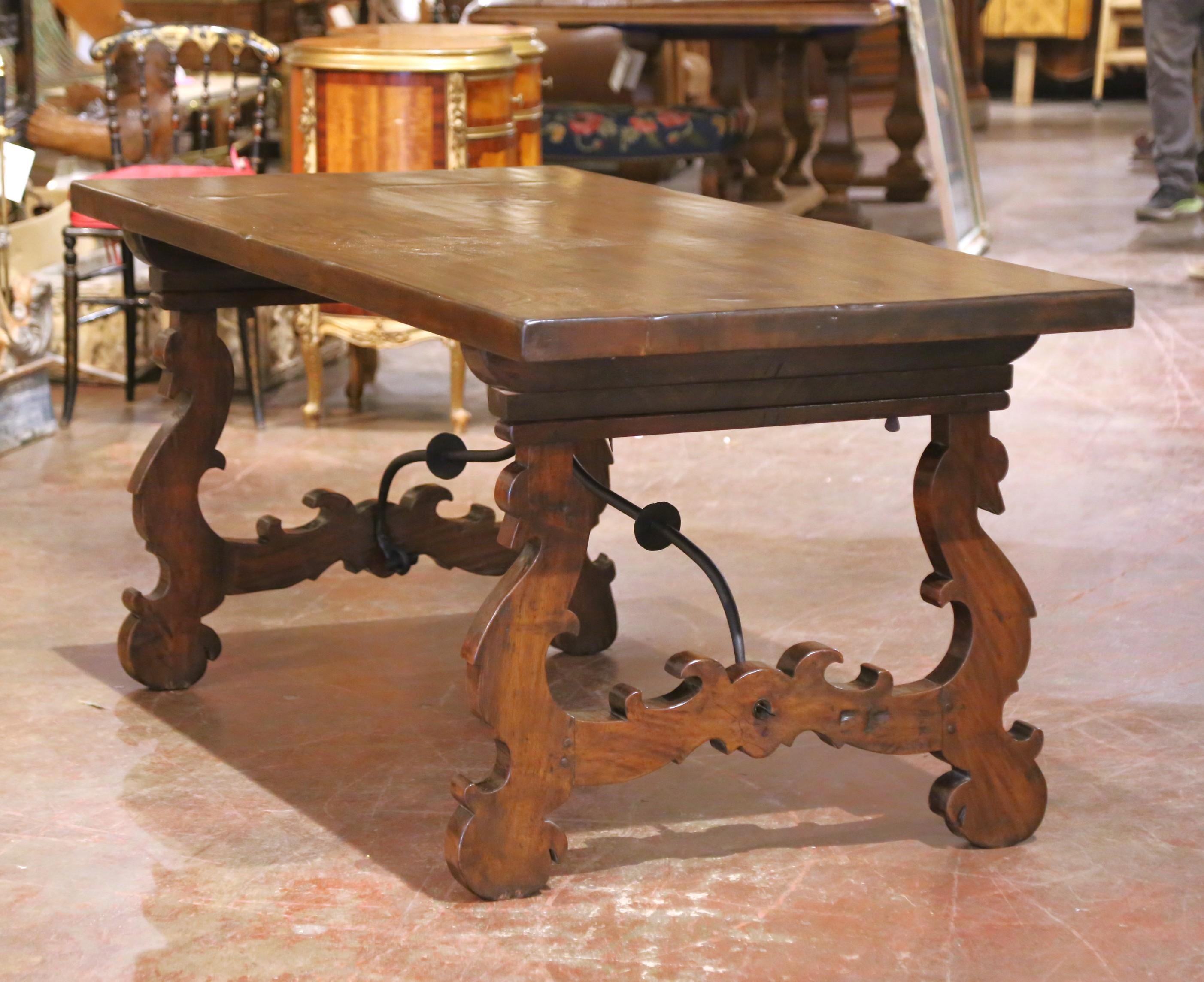 Decorate a dining or breakfast room with this elegant antique trestle table. Hand-carved in Spain circa 1880, the table features a striking single walnut plank top over six feet long, showcasing the natural grain and character of the wood. The wide