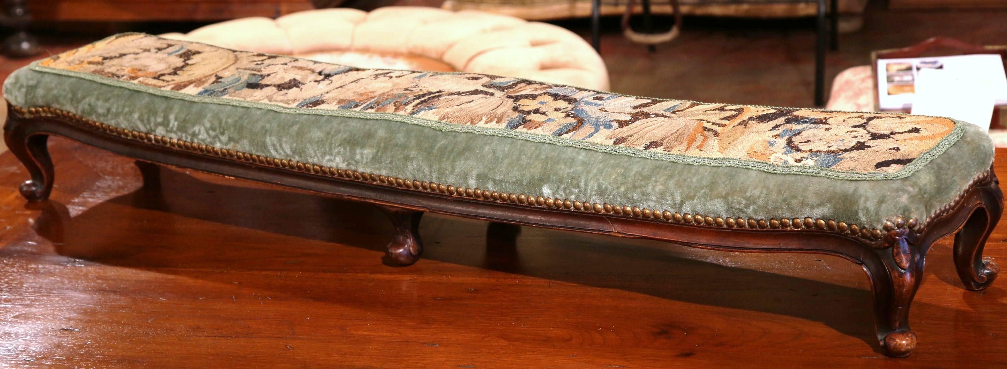 This unique, antique foot stool, or prayer bench, will add color to any home. Created in France, circa 1870, the long fruitwood bench has six legs, curved feet, and a seat upholstered with a green velvet fabric and an 18th century Aubusson tapestry