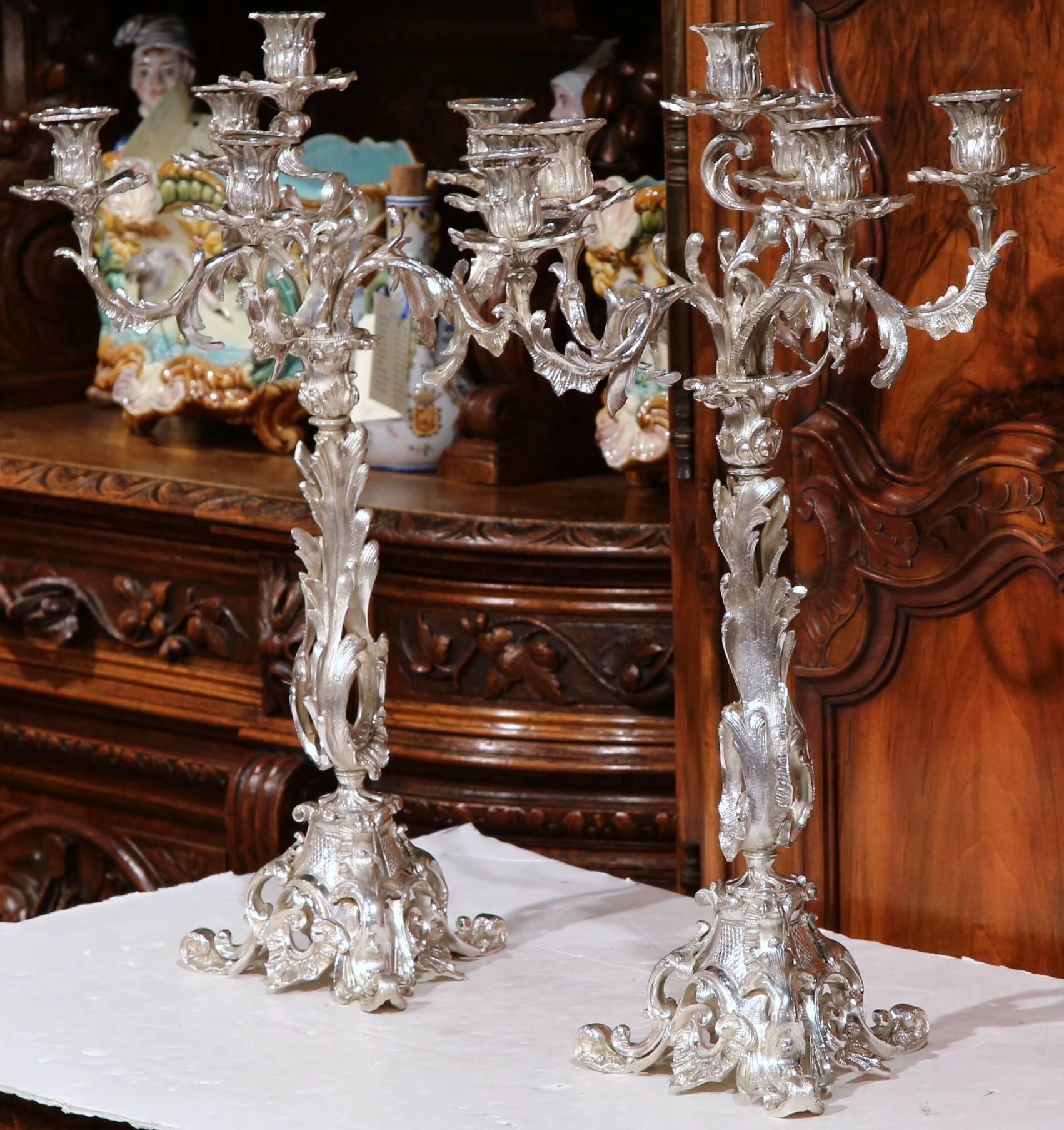 This beautiful pair of tall, bronze candelabras were created in France, circa 1850. Each of the ornate pieces has a silver plated finish and features intricate scrolled work on the stem, the five arms, and the curved feet at the base. This elegant