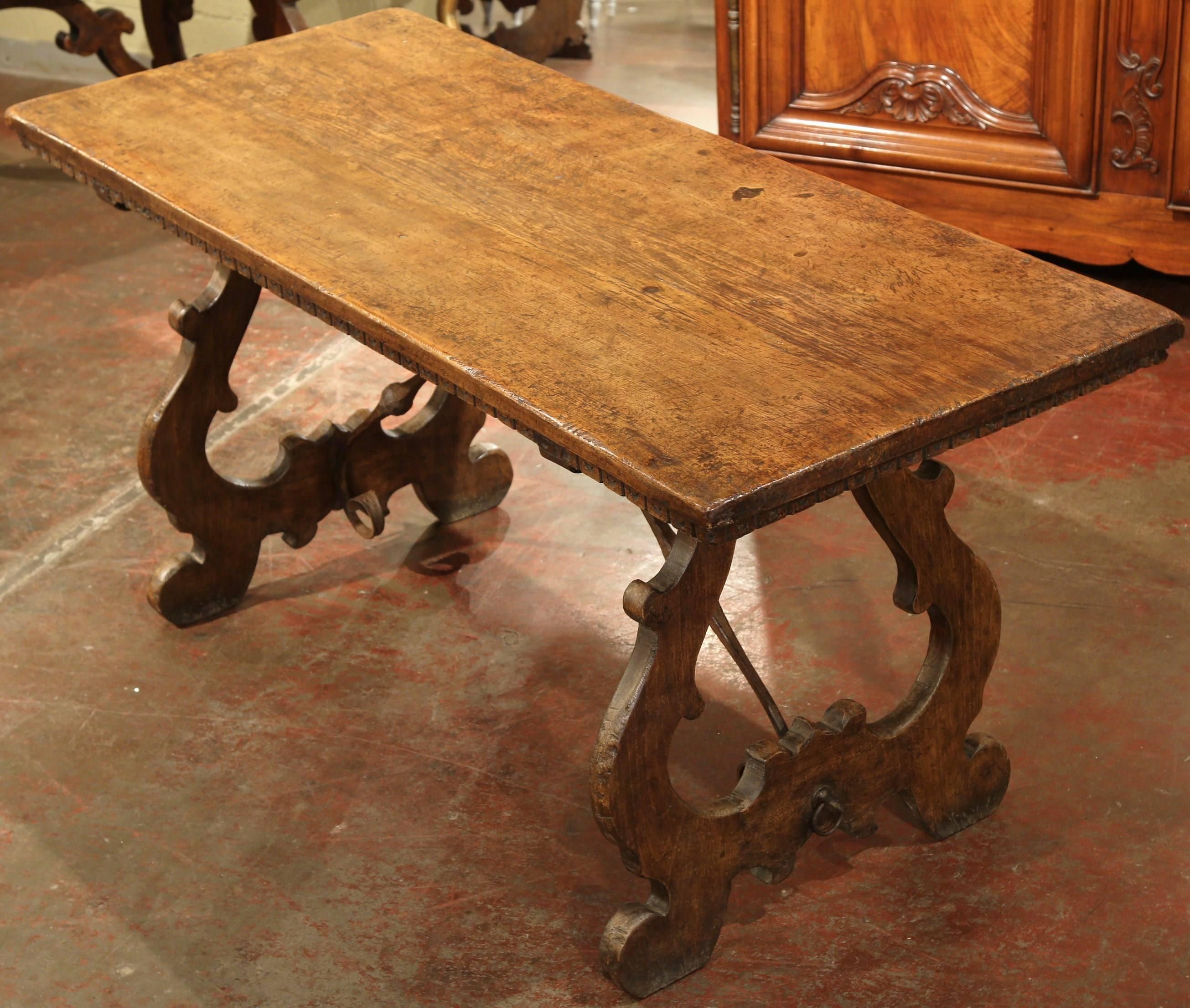 This elegant antique dining room table was crafted in Spain, circa 1850. The fruitwood table has beautiful curved and carved legs, with rounded scroll feet and an forged iron stretcher in between for ultimate stability. The grand tabletop was made