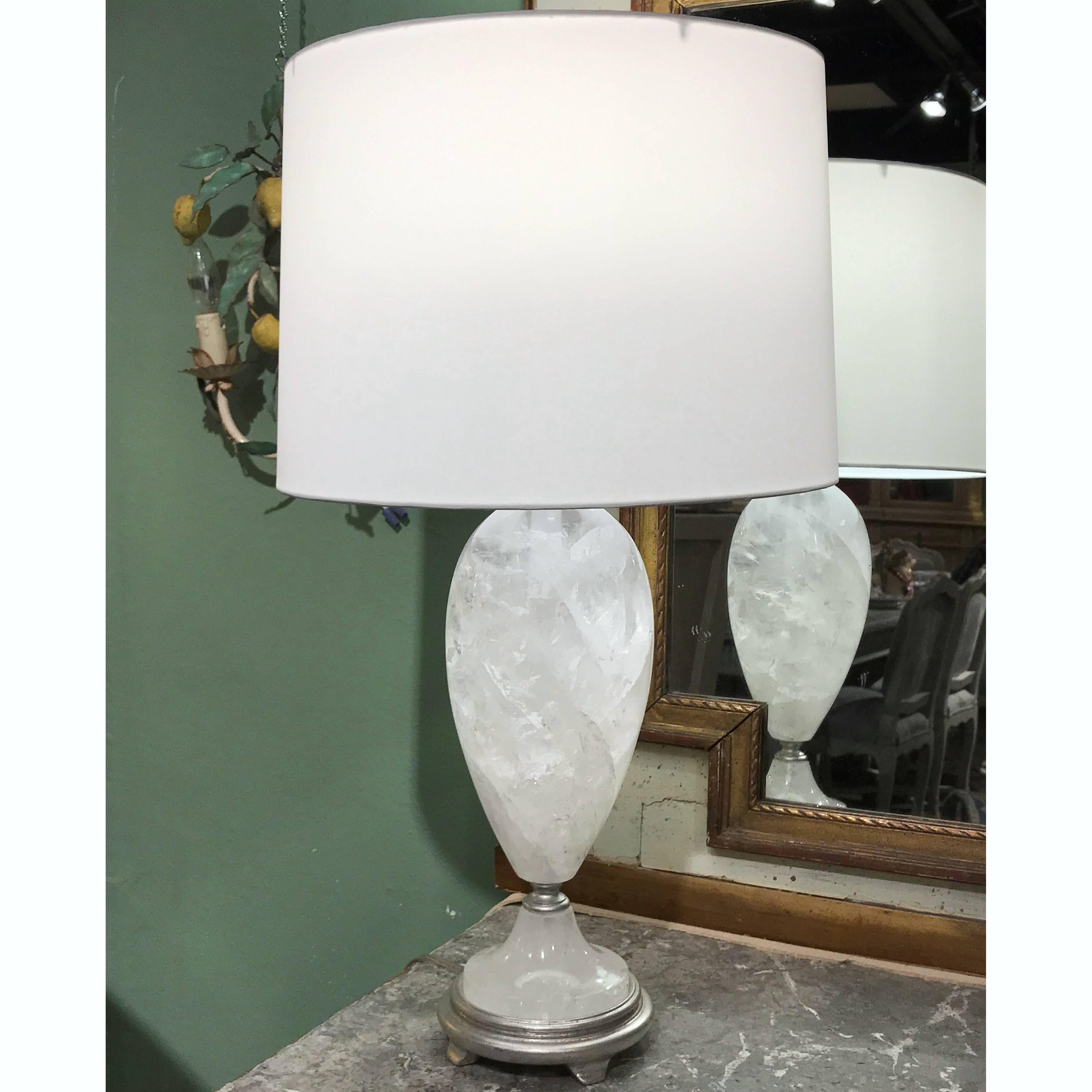 Bring elegance to your formal living room with this sophisticated pair of late 20th century modern rock crystal urns table lamps. The hand-carved, rounded, crystal body of the contemporary lamp is placed on a sturdy wooden base with a silver leaf