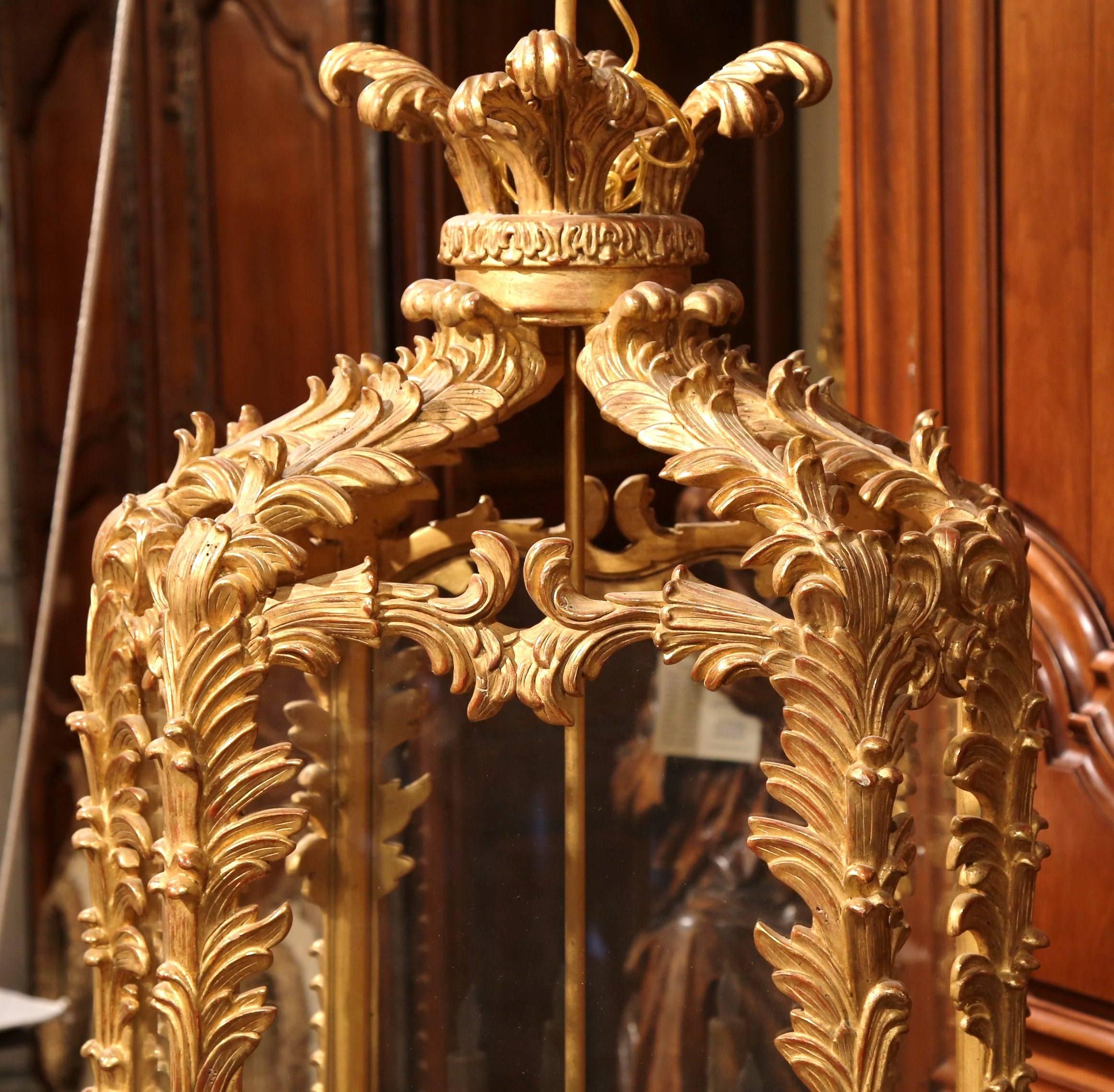 Embellish your entryway with this large carved lantern from France. Created circa 1960, the important hanging lantern features an intricate hand carved glassed frame with six lights centred around a brass stem. The elegant, light fixture has