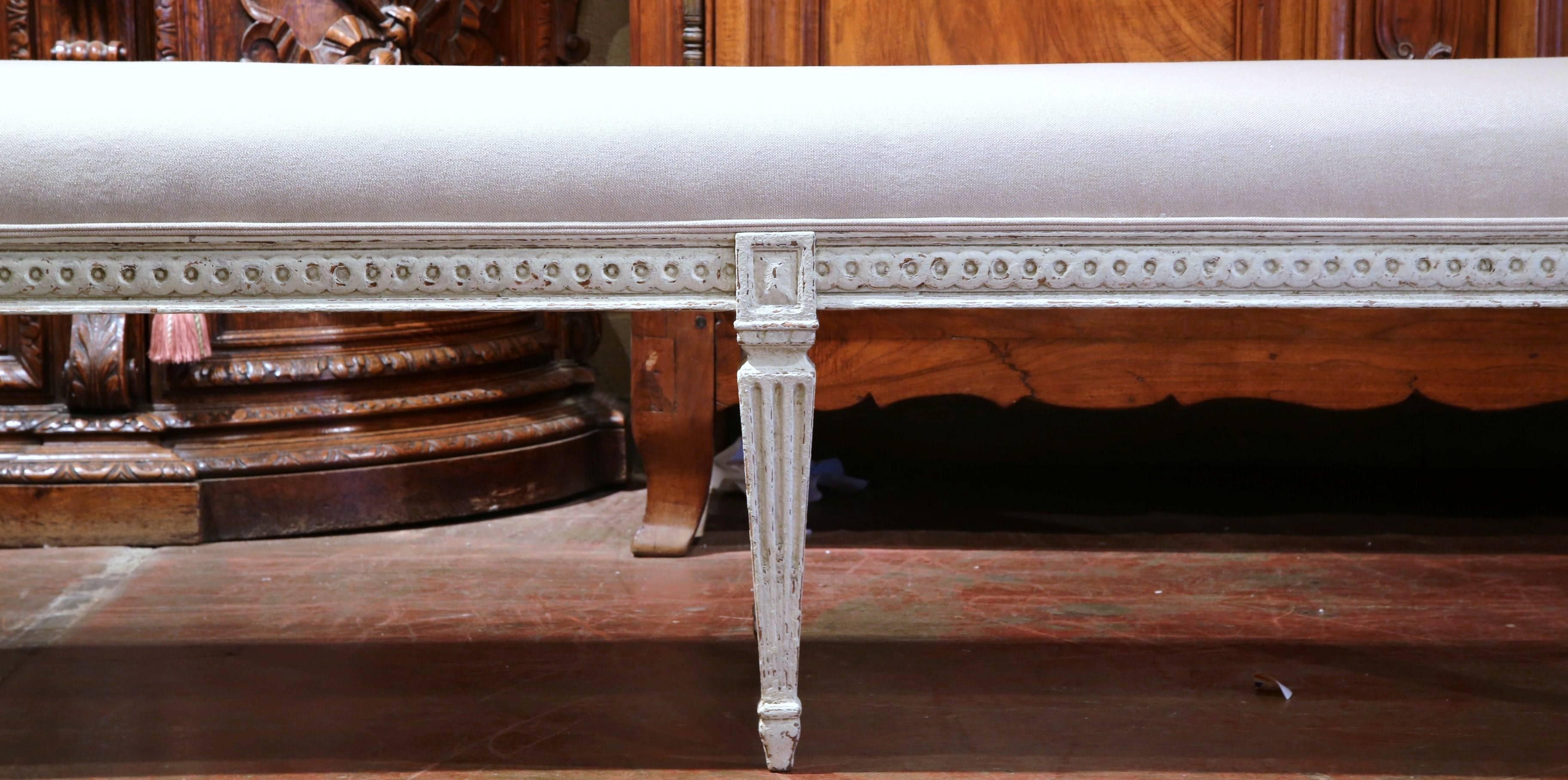 Add extra seating to a hallway, entryway or living room with this nicely carved, Louis XVI bench from France. Carved, circa 1880, the antique bench has six tapered legs, symmetrical carvings around the apron, and is reupholstered with a thick grey