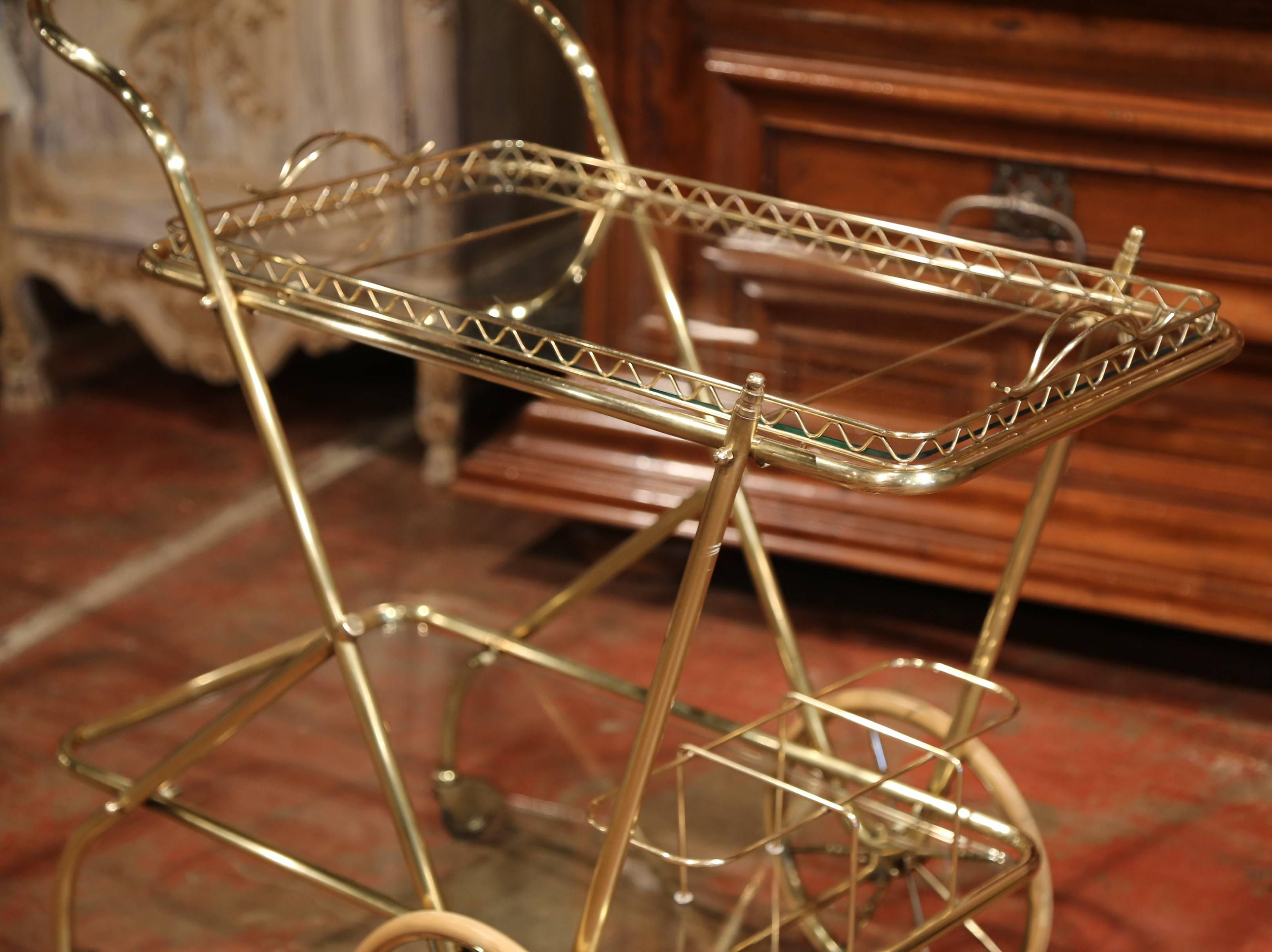 Store your liquors elegantly in this vintage bar cart. Created in France, circa 1930, the table features two glass top tiers and is set over a pair of large rubber wheels with two smaller wheels in the back for easy movement. The side table has a