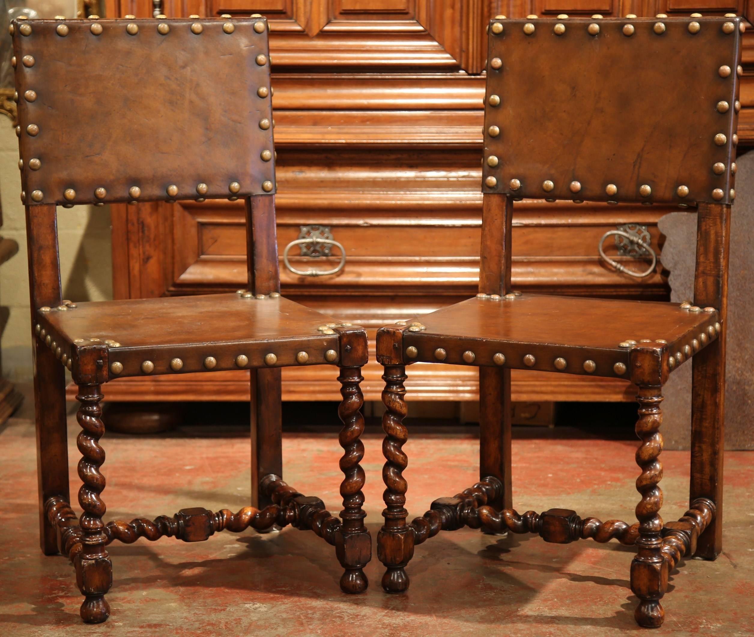 Incorporate extra seating into a study or library with this beautiful pair of antique side chairs from Spain, circa 1900. The chairs feature their original leather, which is embellished with decorative nail head detail. Underneath, the chairs have