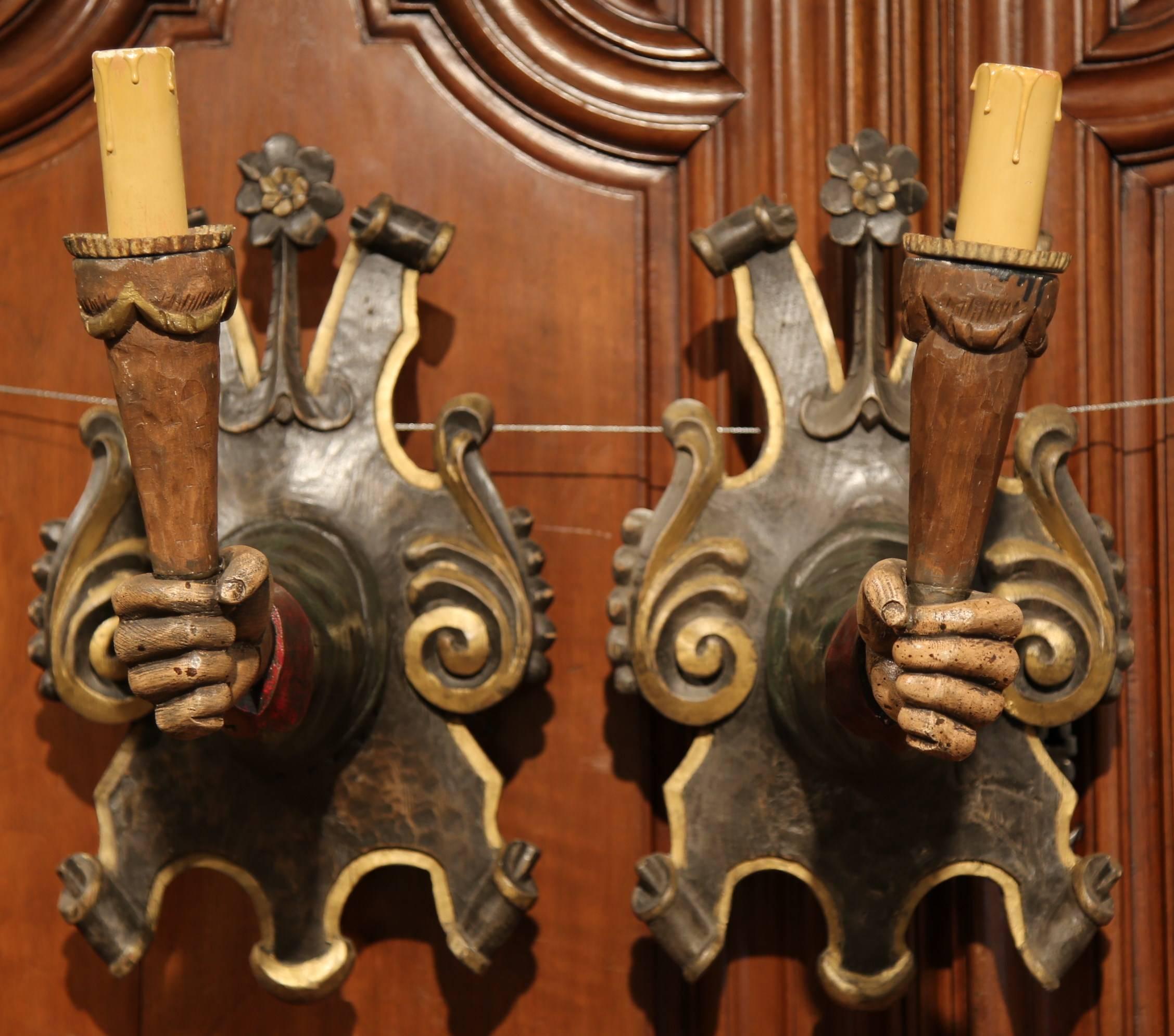 Start a conversation in your home with this interesting pair of Gothic style wall lights from Spain, circa 1920. The unique scones feature a right hand and left hand holding torches. These carved torchères have a polychrome paint finish and are