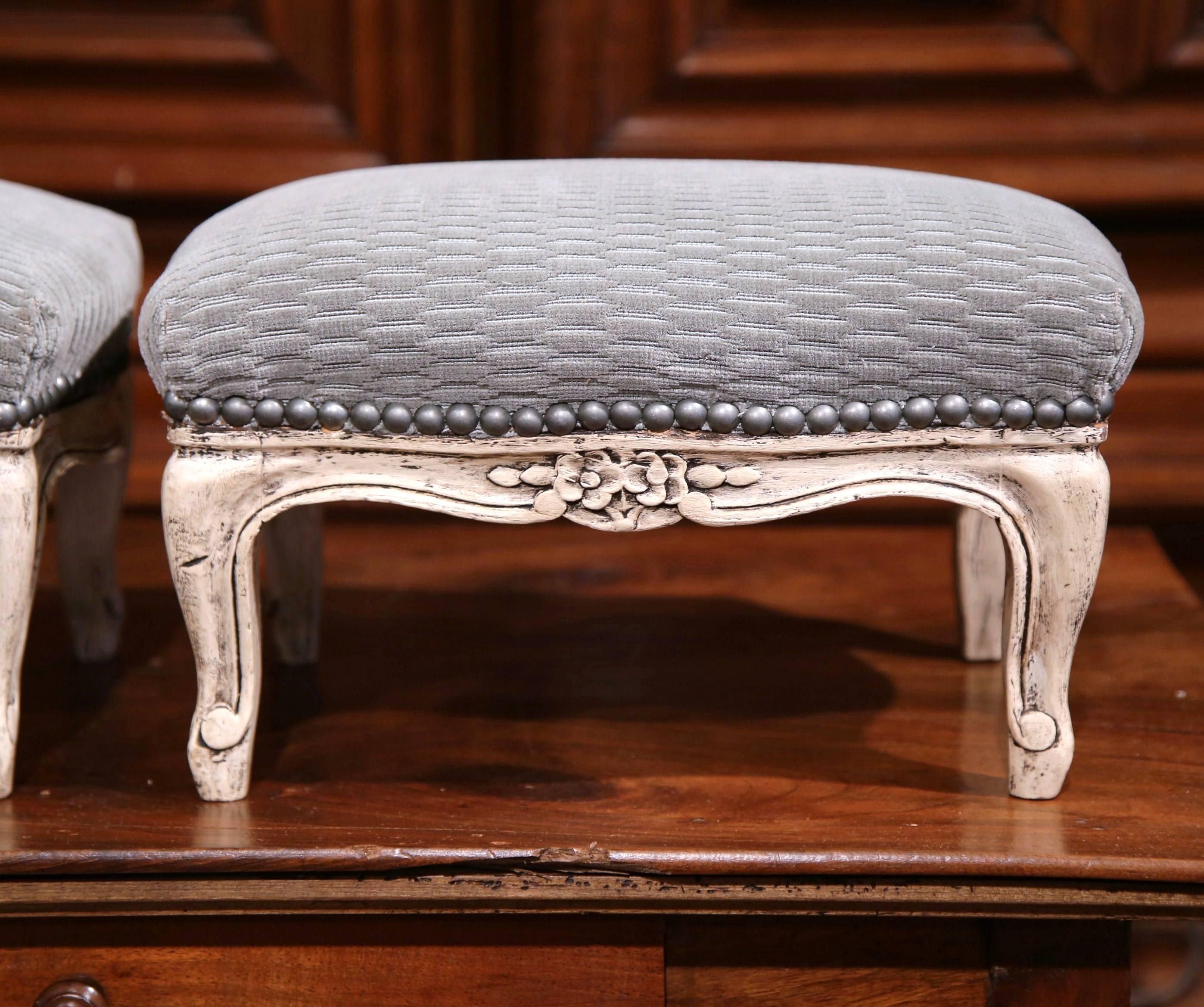 This nice pair of antique foot stools was created in France, circa 1890. Each stool features carved flowers around the shaped apron, cabriole legs and have been reupholstered with a Fine pale blue grey velvet, and are finished with a subtle,
