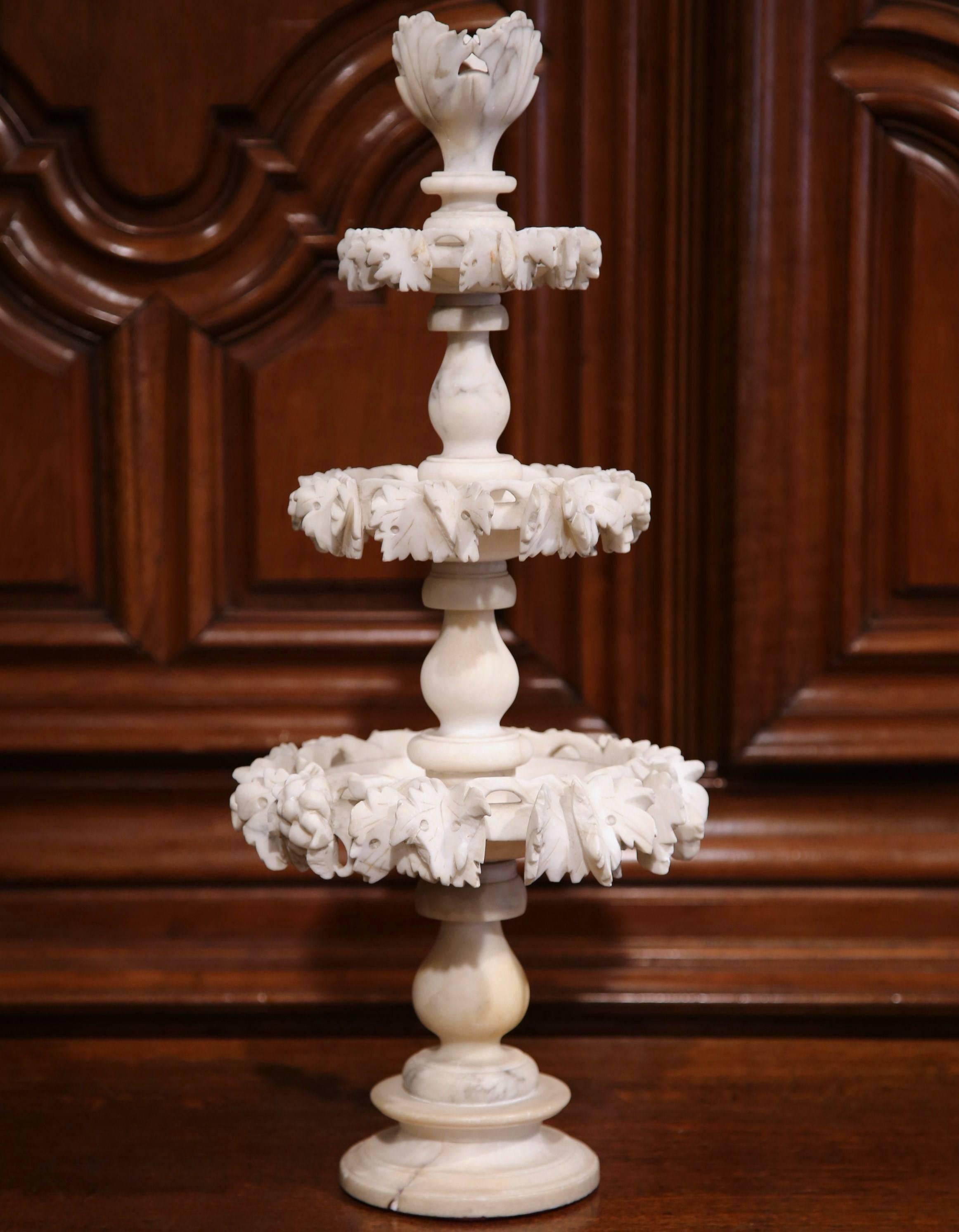 This elegant antique carved alabaster centrepiece was sculptured in France, circa 1880. The display piece stands on a round base and features three, embellished tiers with floral decor, and is crowned with a carved tulip shape, decorative top. The