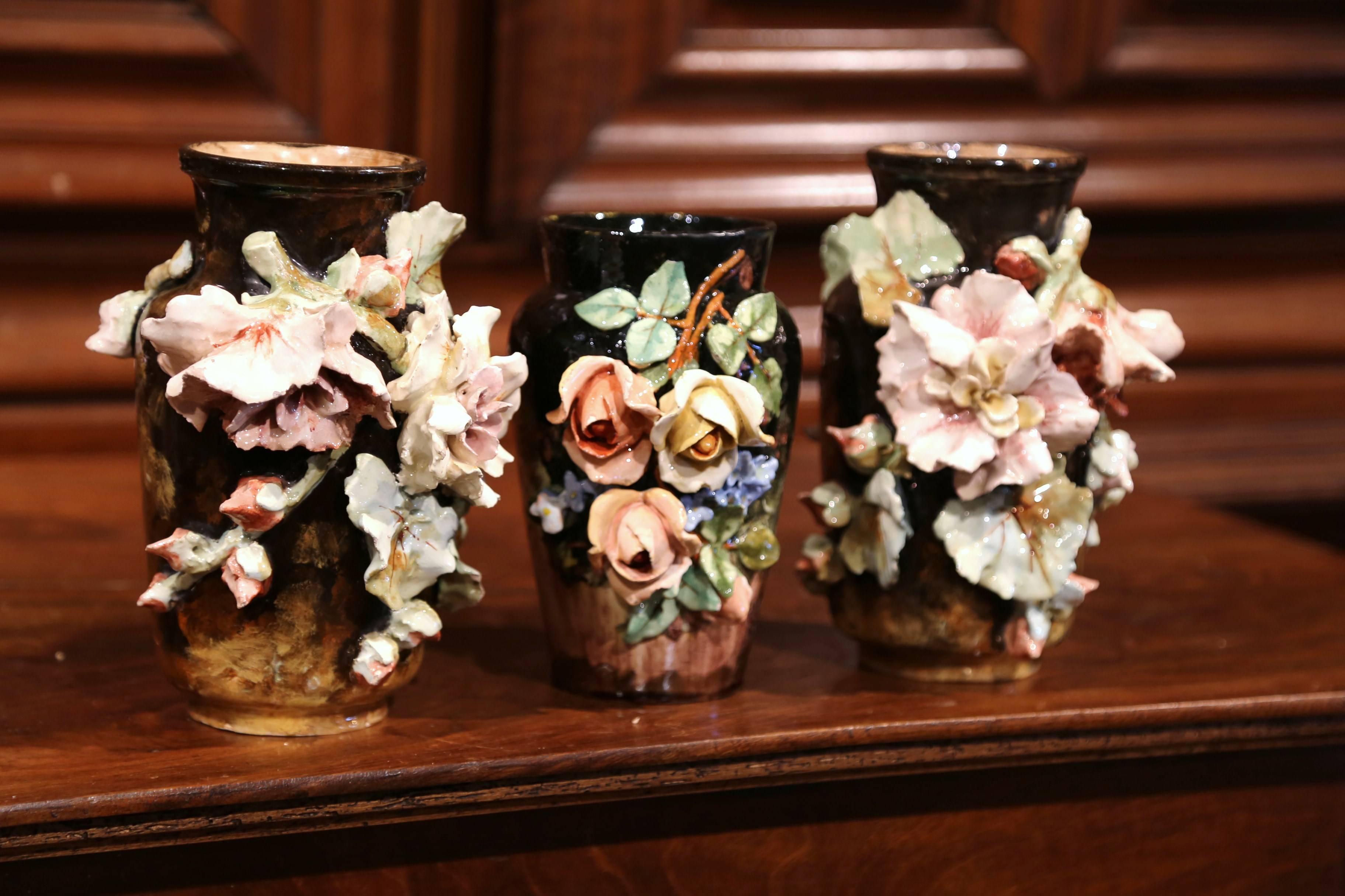 This beautiful, colorful set of three hand-painted Majolica vases were sculpted in Montigny sur Loing, France, circa 1860. Each ceramic vase features soft pink and beige roses with pale green leaves, all in high relief with brown background. The