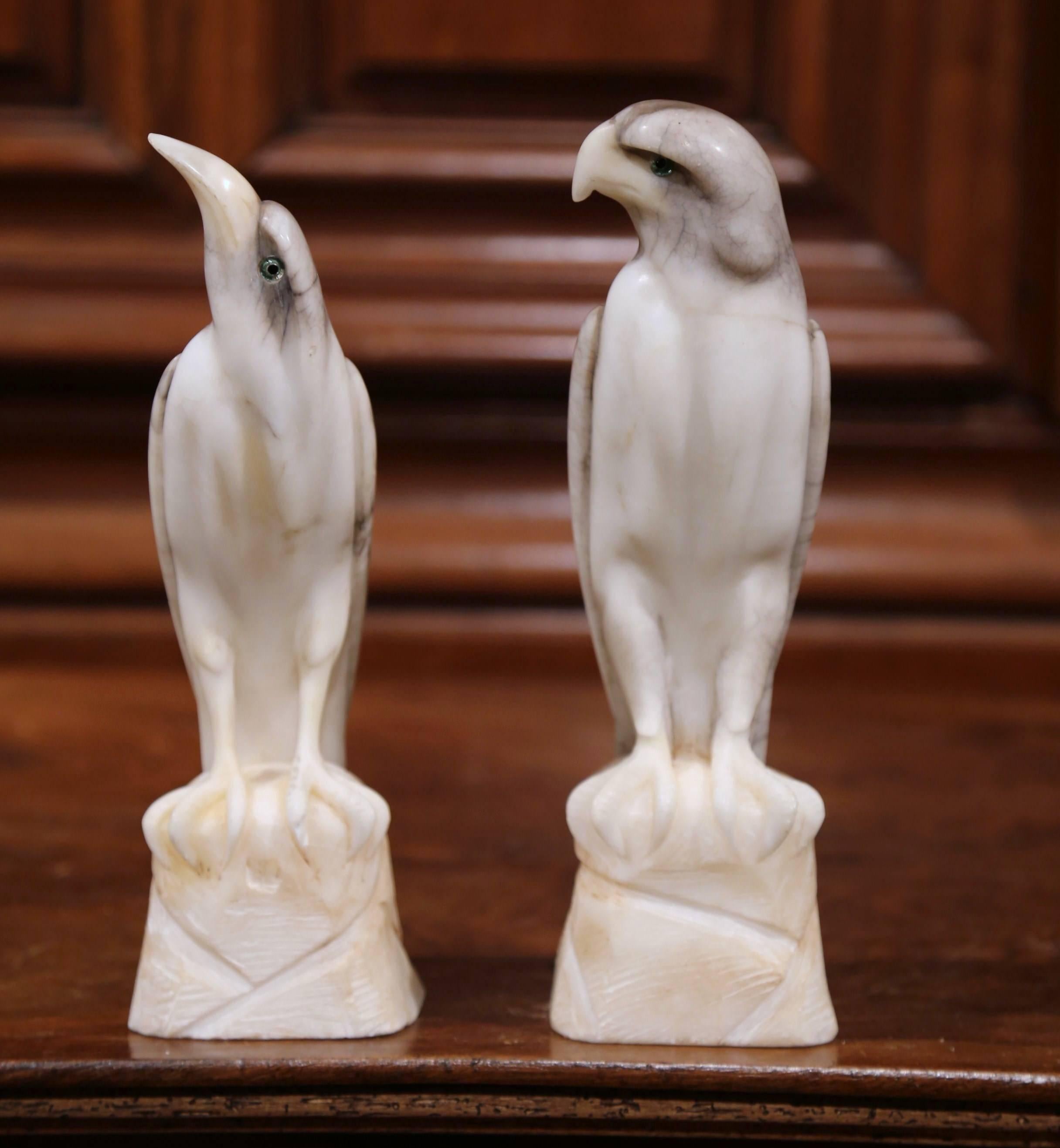 This fine pair of antique birds were carved in France, circa 1880. Each bird - one an eagle, the other a falcon - stands on a rocky base. Both avian figures are carved from gray and white marble, and have glass eyes and beautiful, detailed plumage.