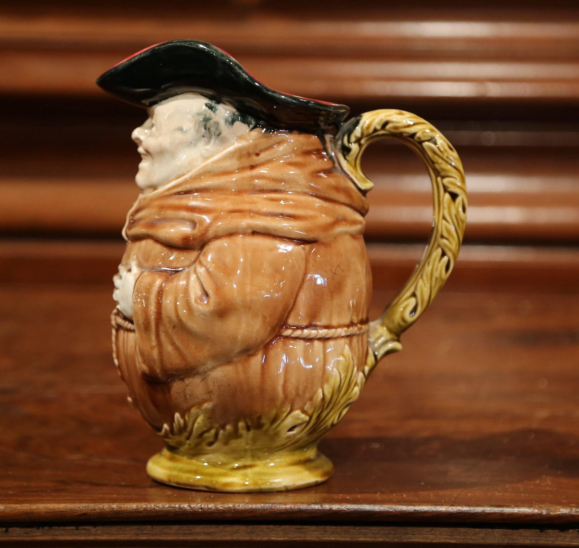 This charming, sculptural majolica pitcher was crafted in France circa 1880. The antique, barbotine jug by Onnaing features a smiling monk with his hands on his chest in a greeting pose. The base and handle are decorated with pale green acanthus